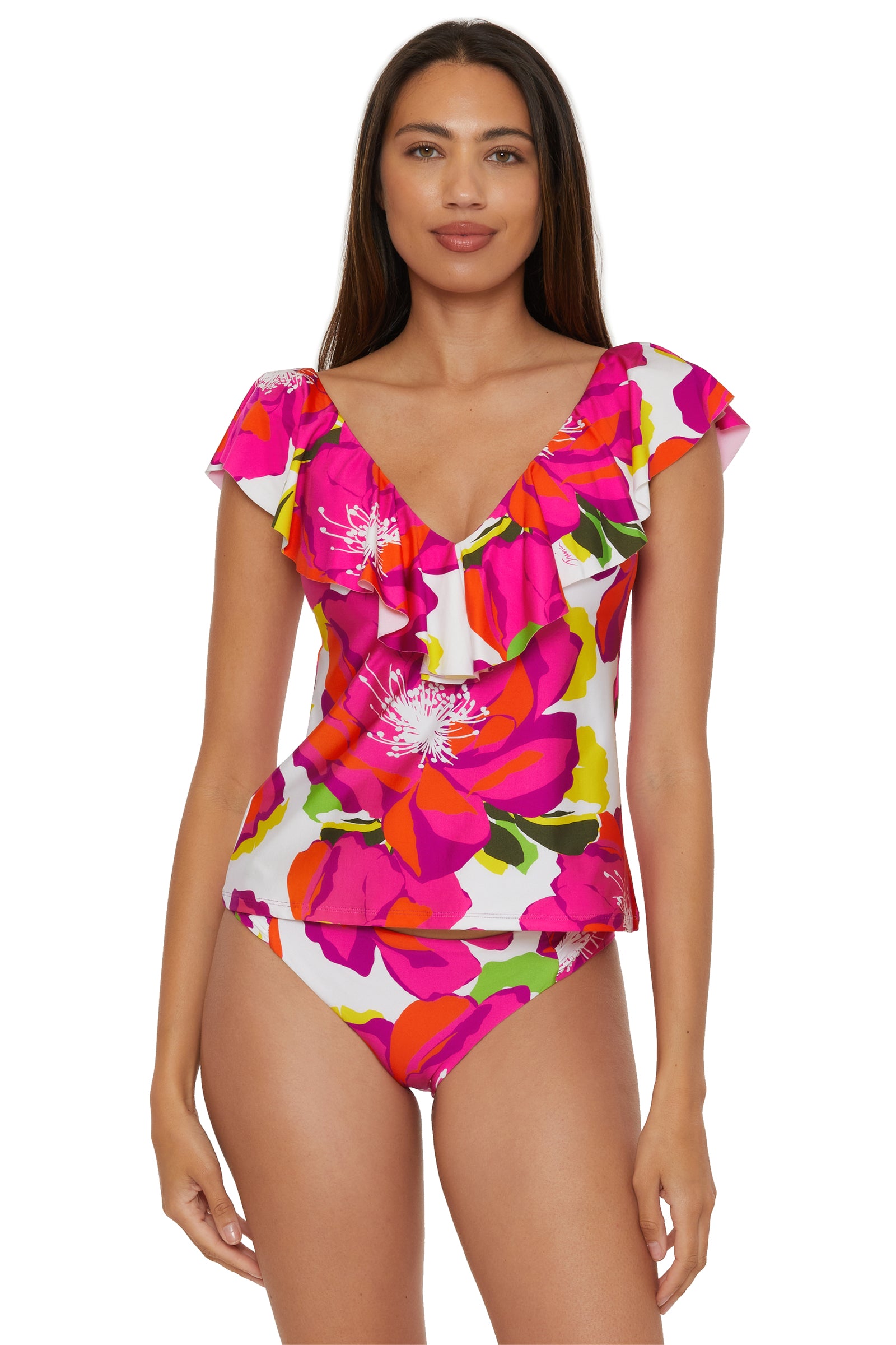 A woman models the Bloom Ruffle Plunge Tankini in Multi, featuring a ruffled V-neck and bold floral print with matching bikini bottoms, standing against a plain white background.