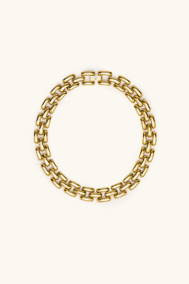 The Phoebe 17 Necklace in gold, featuring bold, thick rectangular links arranged in a circle on a plain light background. Displayed flat, it highlights its striking interlocking link design.