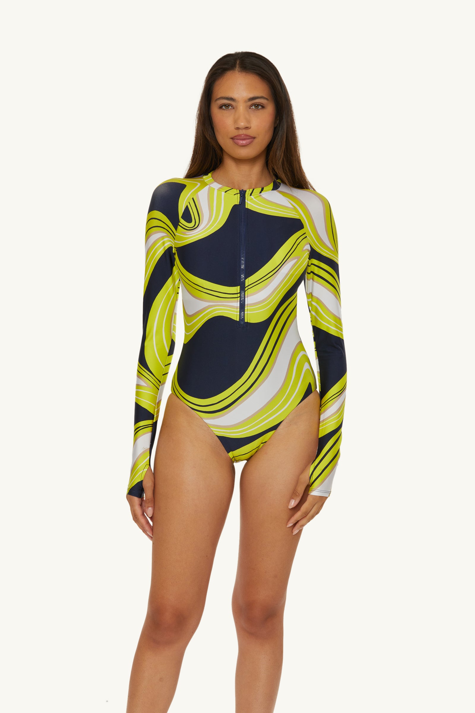 A woman faces forward wearing the Long-Sleeve Zip-Up Paddlesuit in Serena Swirl Swim, featuring a front zipper and a wavy abstract pattern in navy, yellow, white, and light grey.