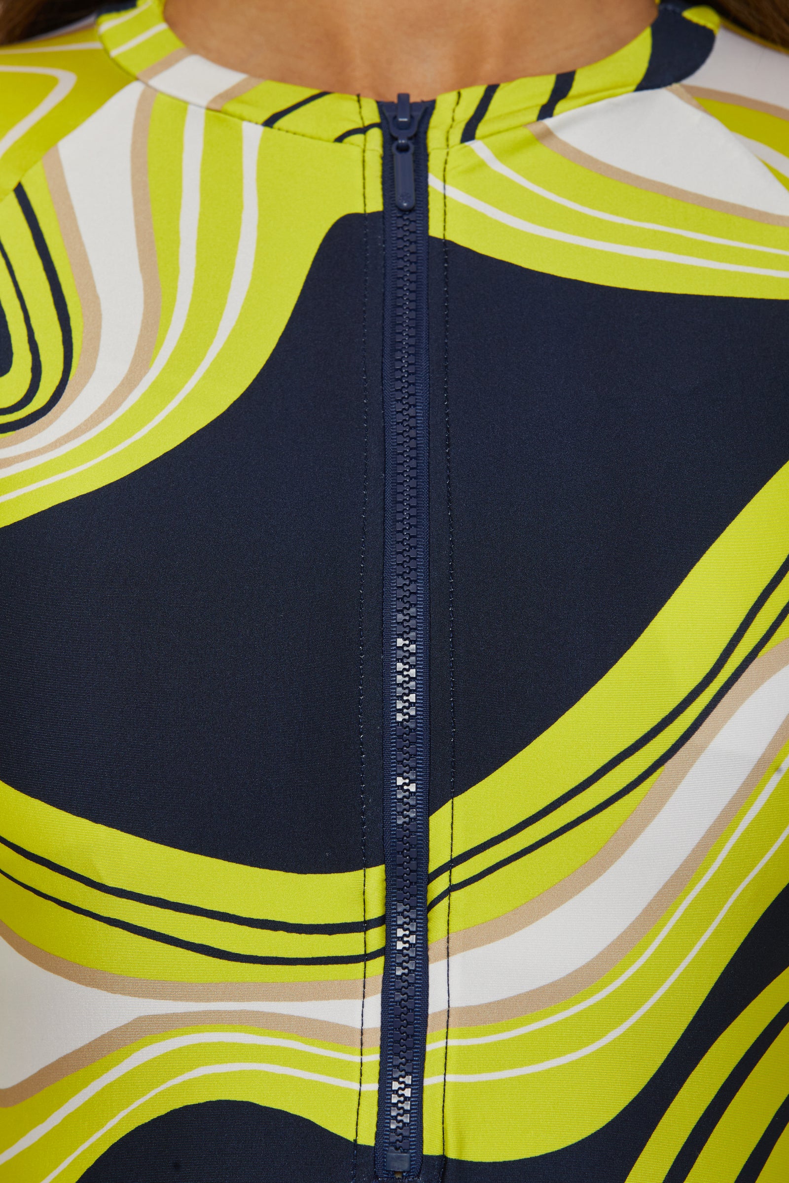 Close-up of the Long-Sleeve Zip-Up Paddlesuit - Serena Swirl, featuring a central navy zipper and bold wavy stripes in yellow, white, beige, and navy for a dynamic, modern look.
