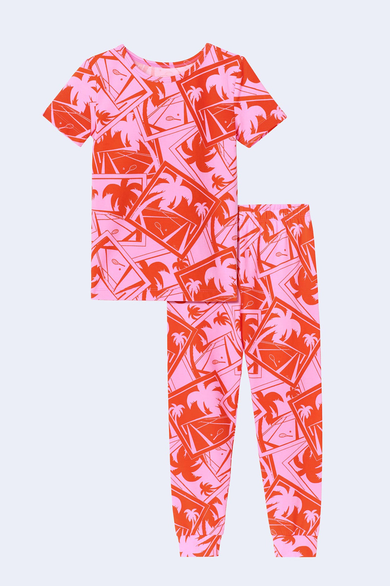 The Pink Kids PJ Set - Tennis Stretch Jersey includes a short-sleeve top and long pants with a light purple background and pink/red tropical print featuring palm trees and sunset scenes.