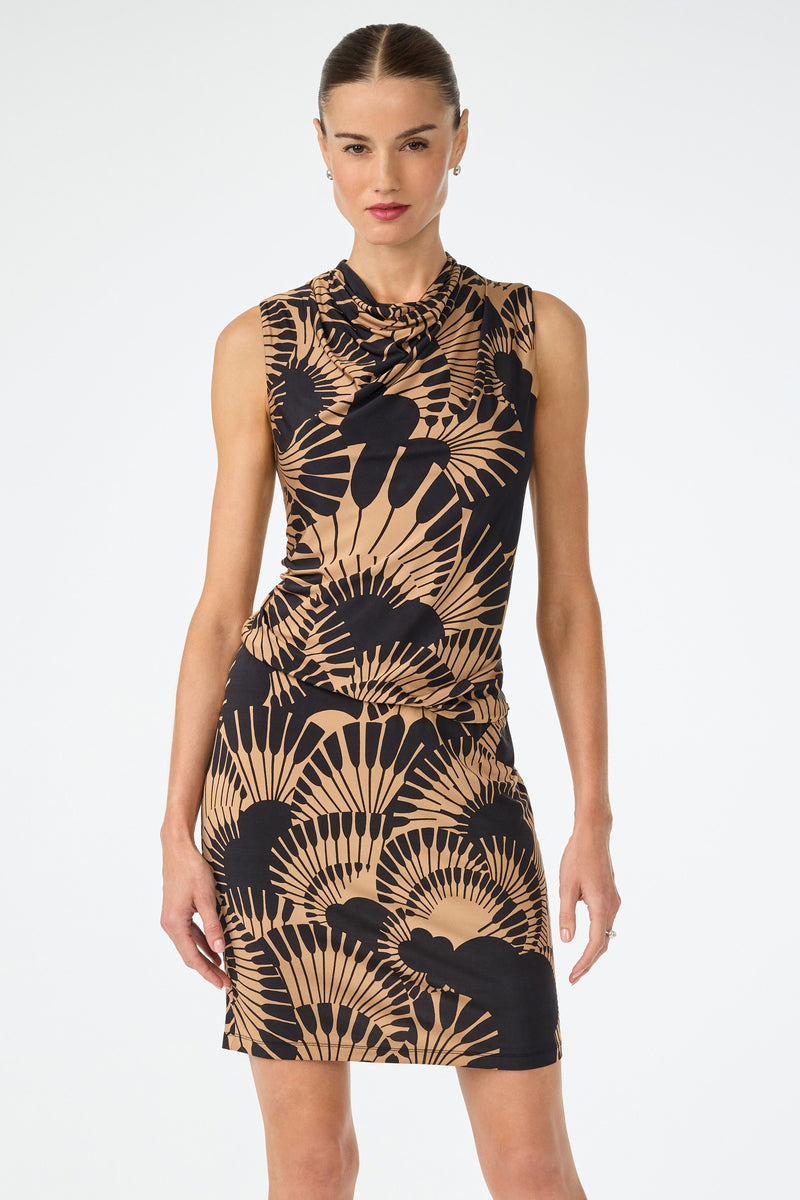A woman stands against a plain white background wearing the Lenaya 3 Drape Dress in Juniper Jersey, a sleeveless, fitted style featuring a bold black and tan abstract leaf print. Her hair is slicked back and she looks forward with a neutral expression.