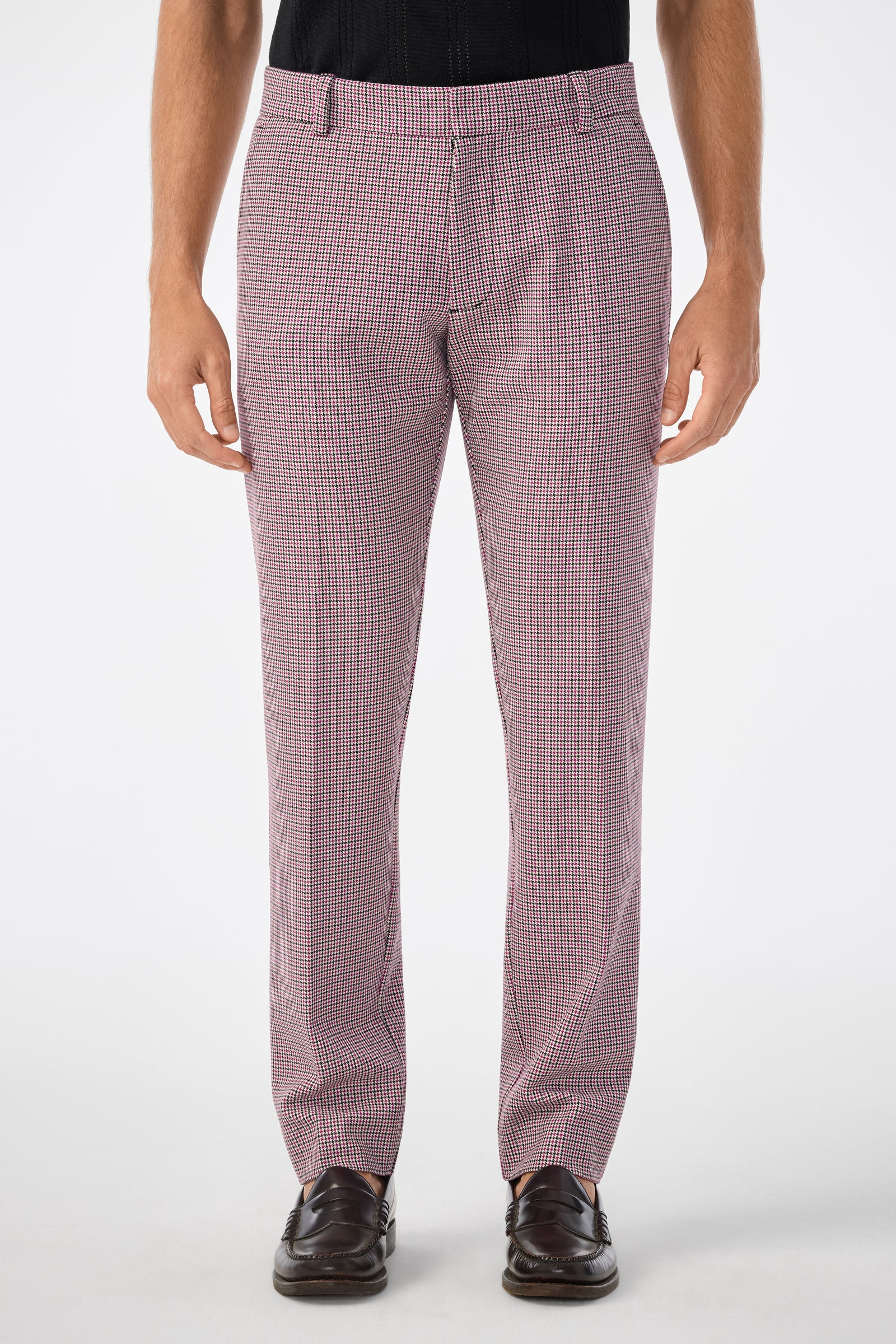 A man wears Clyde Slim Trousers in red and white small check print with dark brown loafers, standing forward, cropped chest down, against a plain white background.