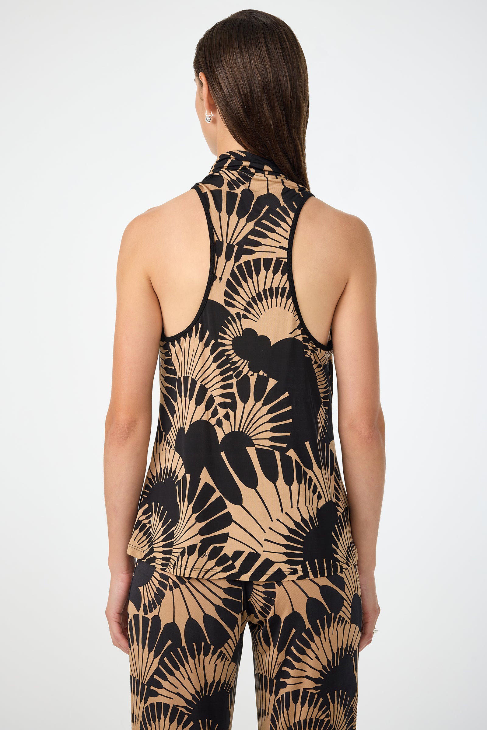 A person with long, straight brown hair wears the Mosiac Cowl Neck Top in Juniper Jersey, paired with matching pants featuring a bold black and beige abstract fan pattern, seen from the back against a plain white background.