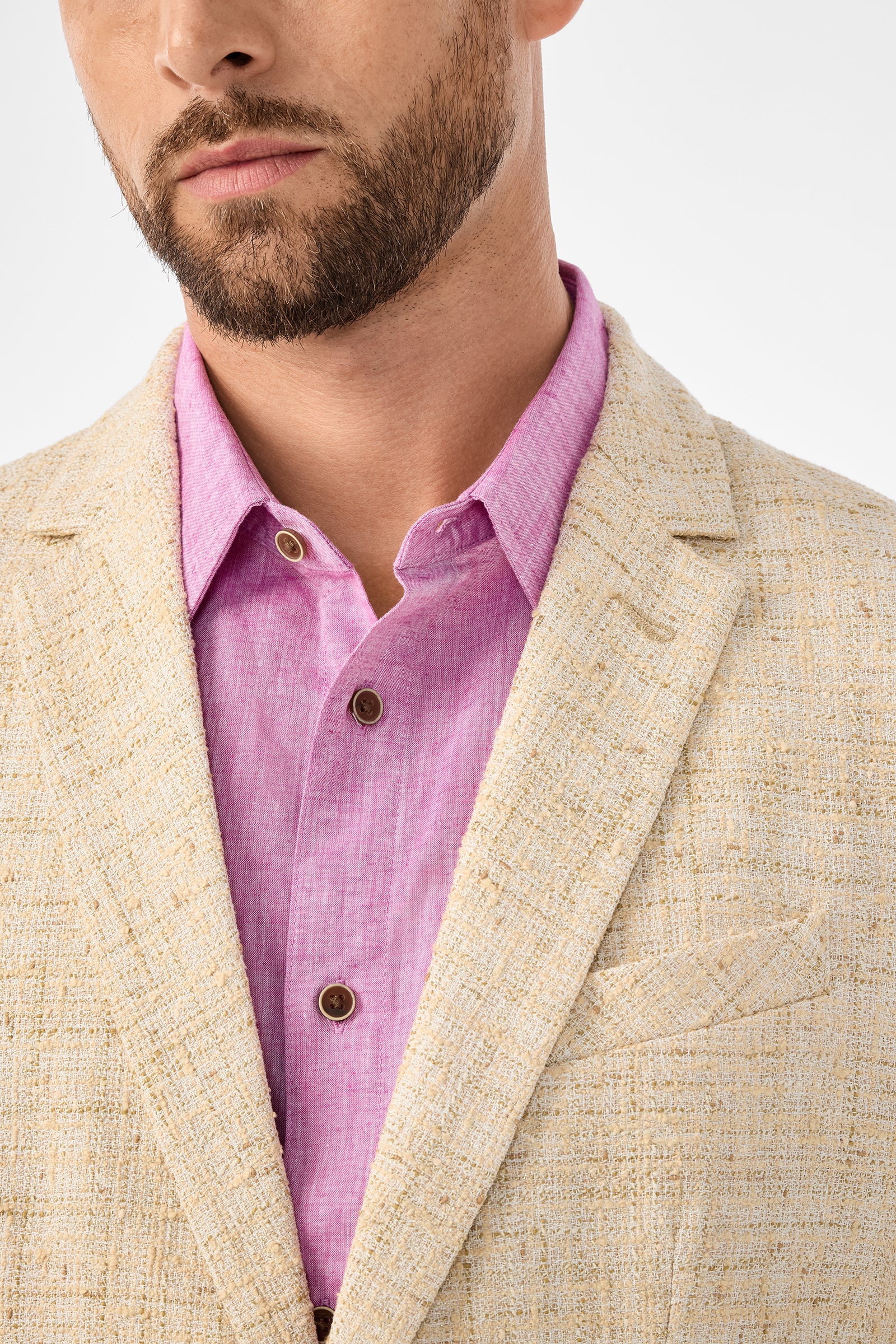 A man models the Thurston Blazer in beige over a pink button-up shirt. Only his lower face and upper torso are visible against a plain, light background.