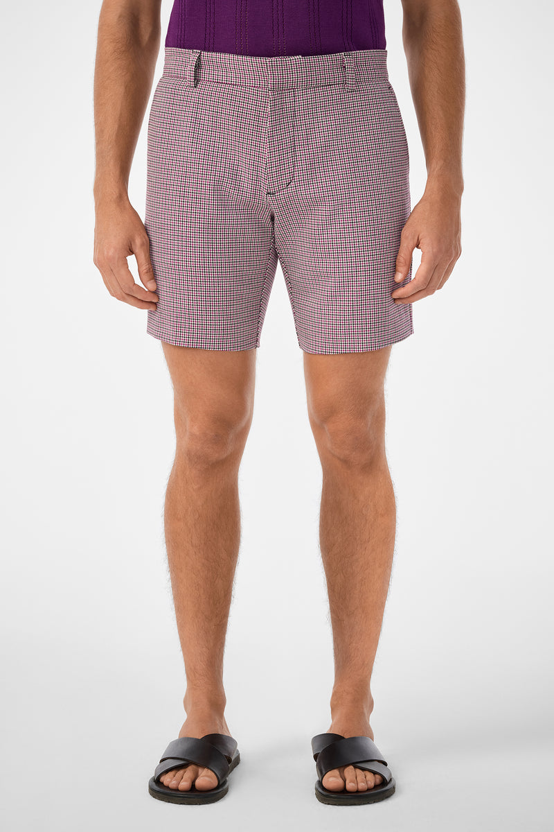 A person stands facing forward wearing a purple textured shirt, Lawrence Short in red and white pattern, and black sandals. The image shows them from mid-torso to feet against a plain white background.