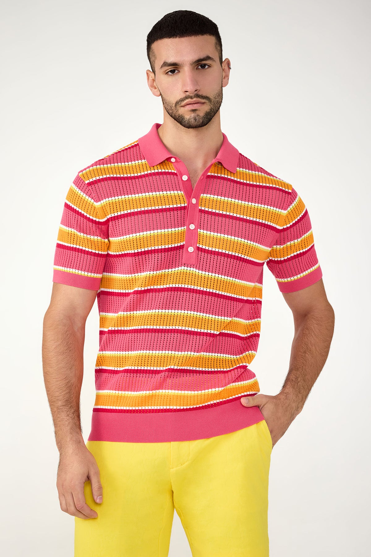 A man with short dark hair and a beard wears the Viviano Short-Sleeve Mesh Polo in Multi, paired with yellow pants, while standing against a plain light background.