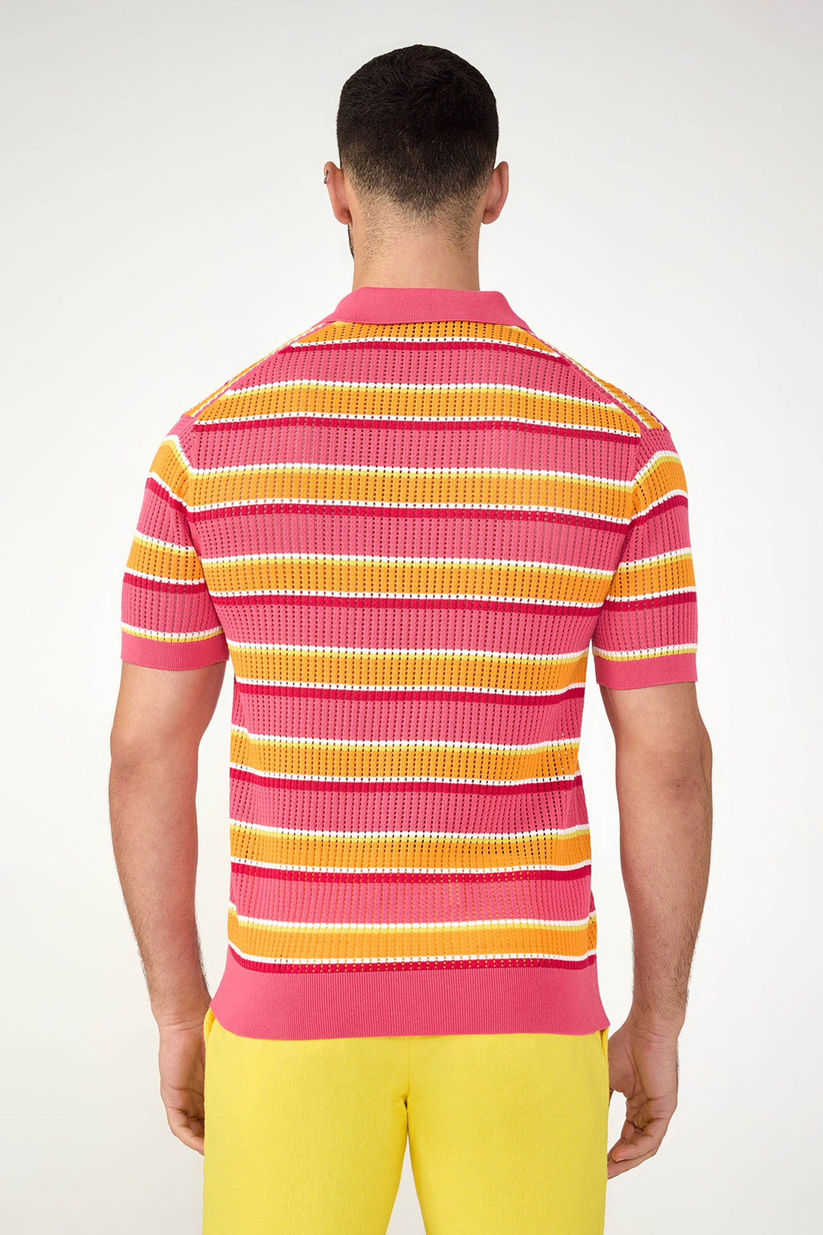 A man faces away wearing the Viviano Short-Sleeve Mesh Polo with pink, orange, yellow, and white stripes, paired with bright yellow pants against a plain white background.