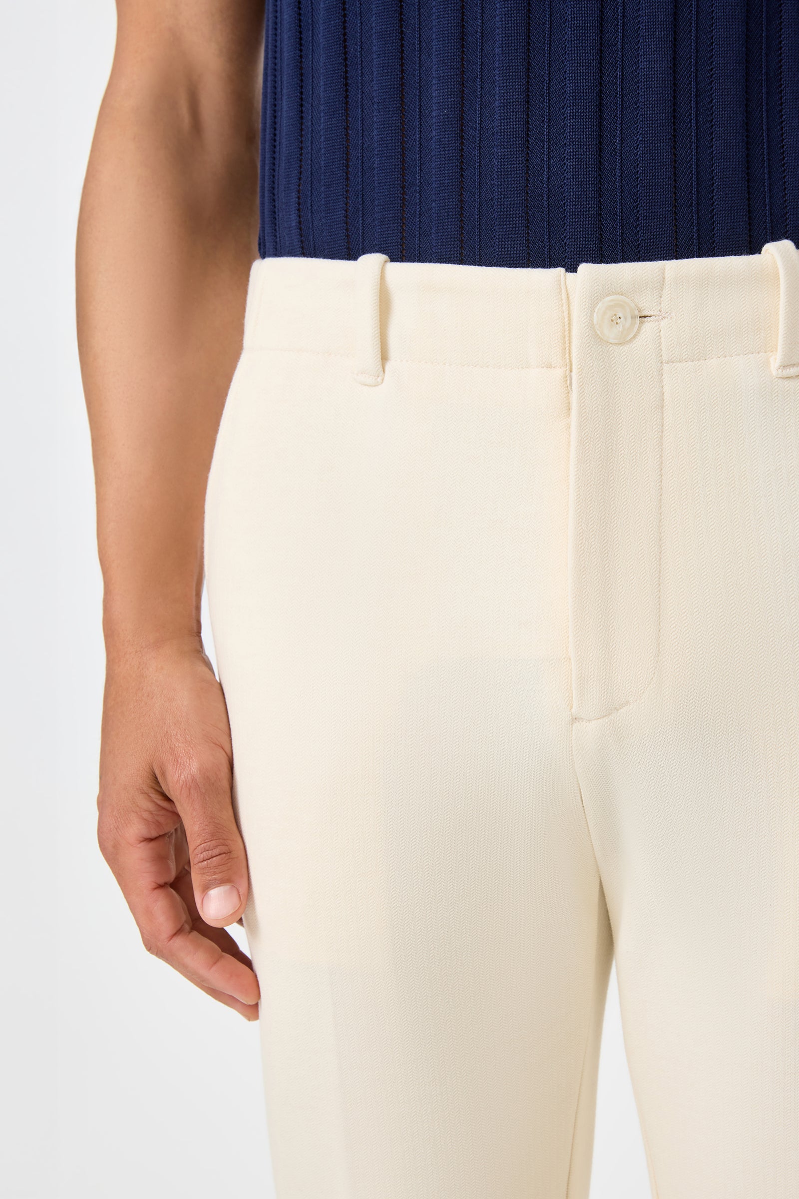 A person wearing the Alex Slim Trouser - Ecru; only their torso and one hand are visible against a plain light background.