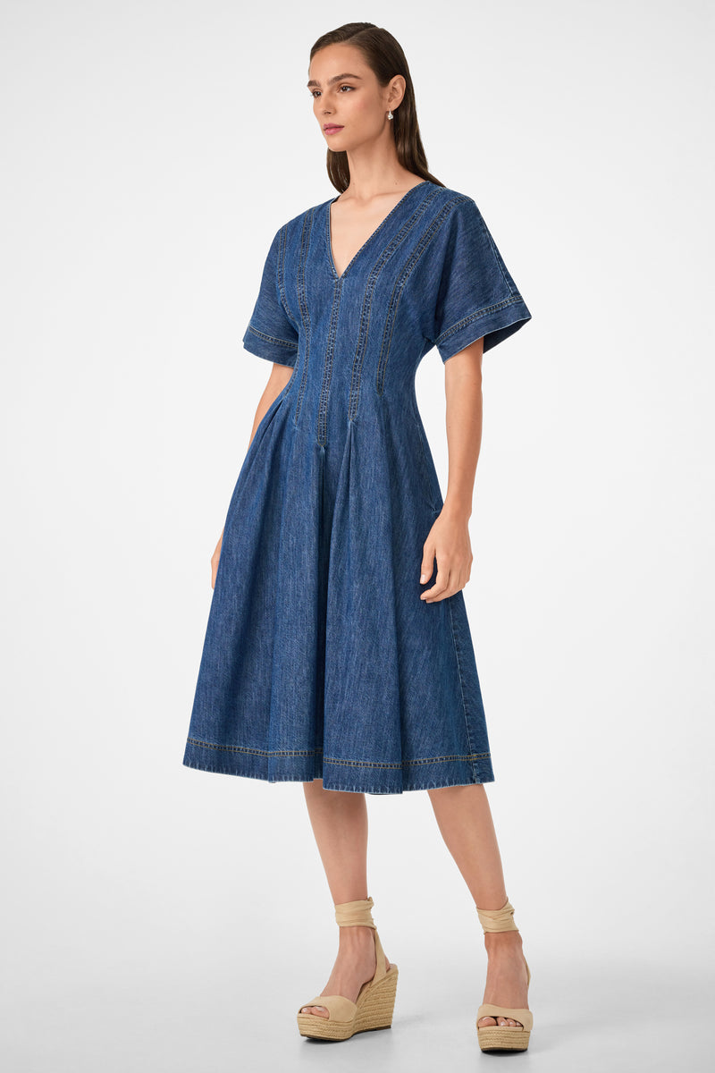 A woman wearing the Ashe 2 Short-Sleeve Denim Dress, featuring a knee-length, V-neckline and flared skirt, paired with beige wedge espadrilles, stands against a plain white background.
