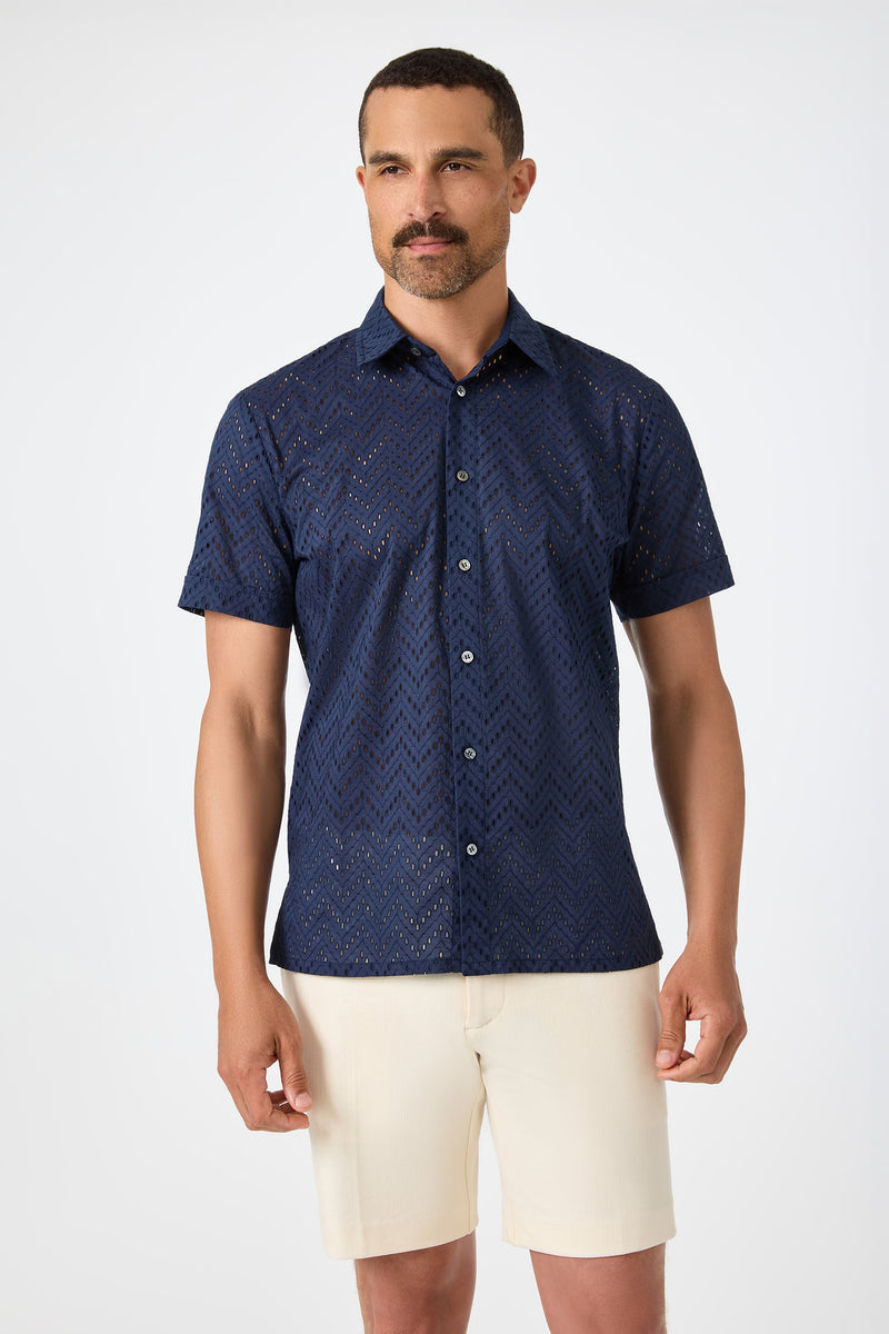 A man wearing the Branson Shirt - Cotton Eyelet in Ink and beige shorts stands against a plain white background.