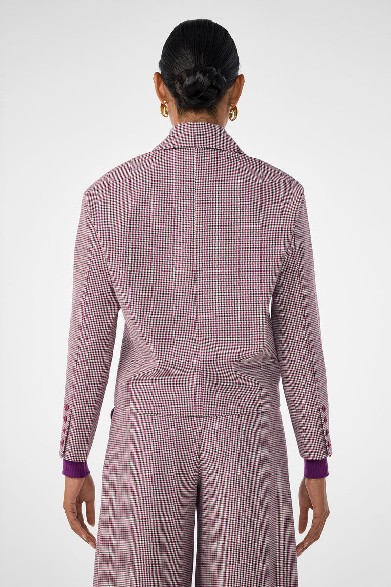 A person with dark hair in a neat bun is shown from behind, wearing the pink and white checkered Ayla Jacket with matching wide-leg pants and gold hoop earrings against a plain, light-colored background.