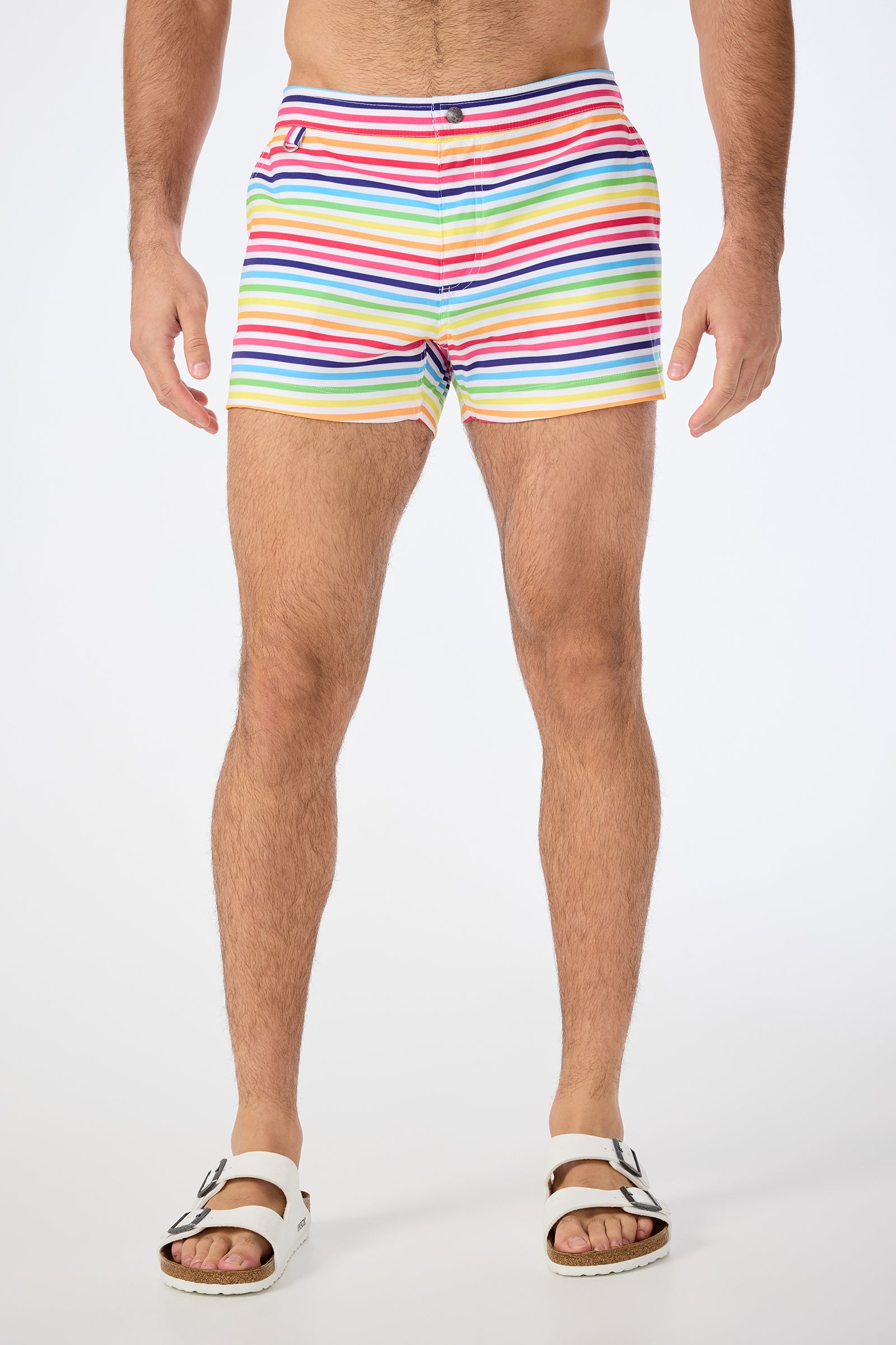 A person stands against a plain background, wearing the Chico Swim Trunk - Pride in Multi and white buckle sandals. The image is cropped from the shoulders down.