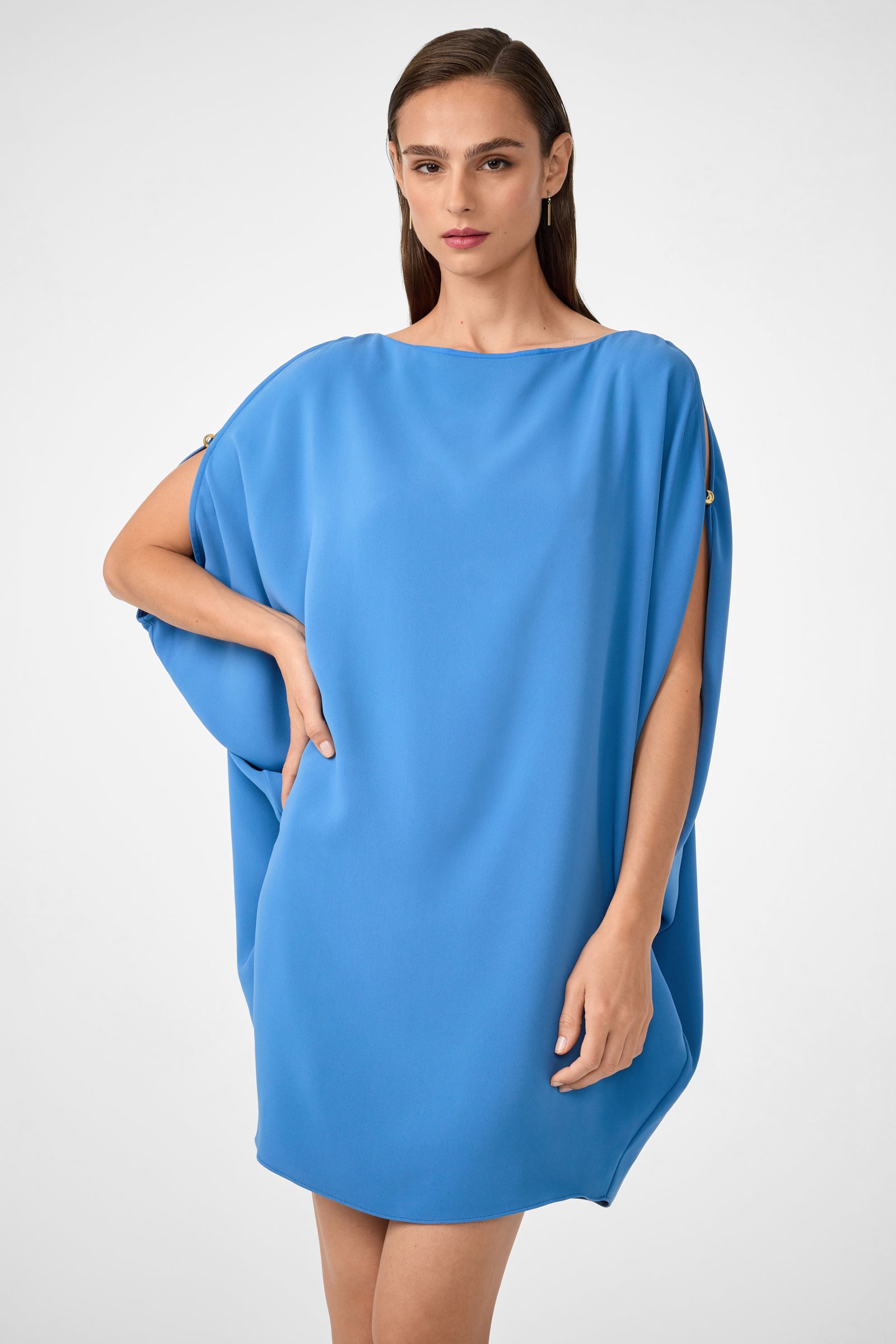 A woman models the Razu Short Split Sleeve Mini Dress, a loose-fitting bright blue style with gold button accents on the shoulders, standing against a plain, light background with a neutral expression.