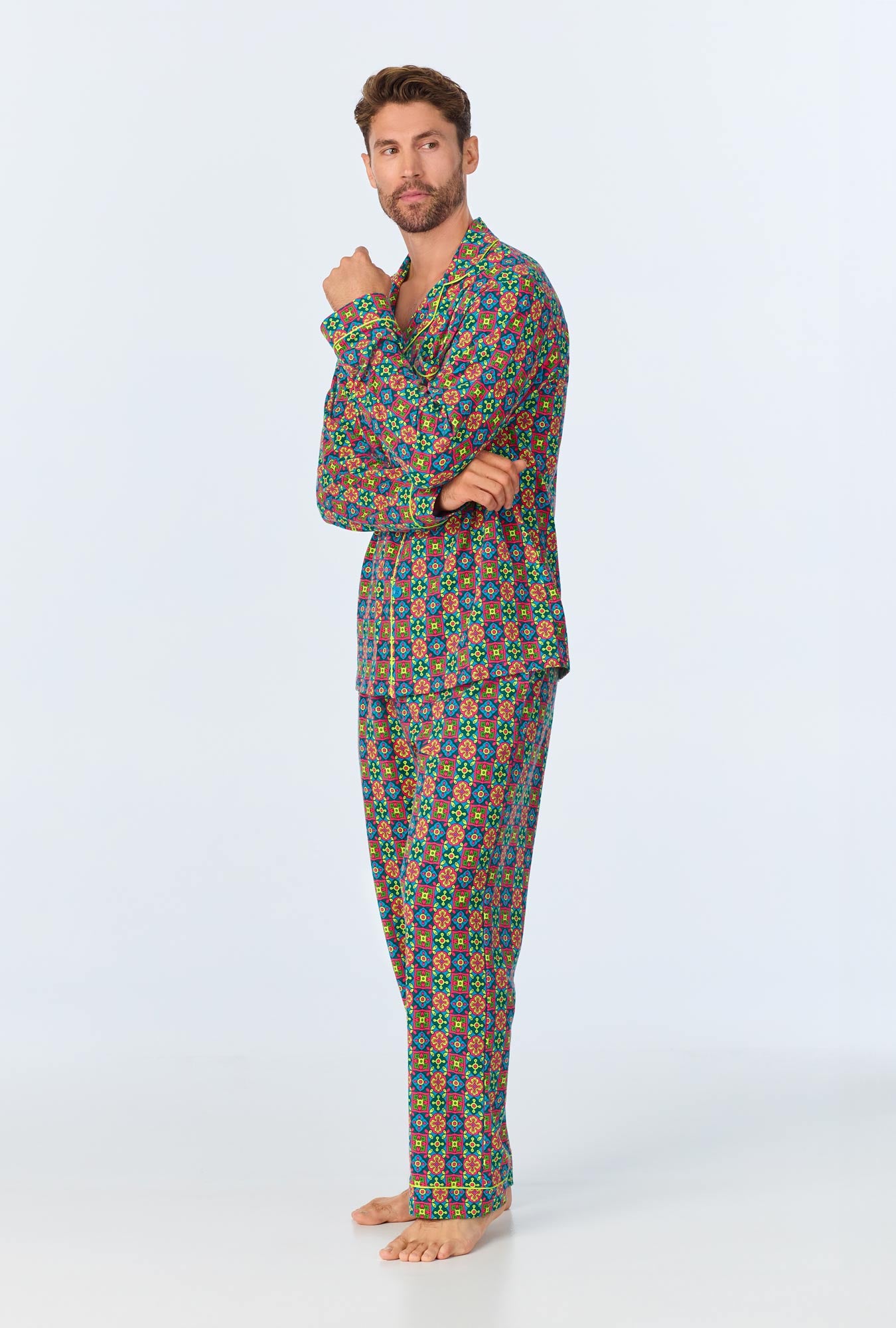 A man with short hair and a beard stands barefoot against a plain background, wearing the Pretty Tiles Mens Long Sleeve Long Pant Jersey PJ Set. He looks at the camera with one hand touching his chin.