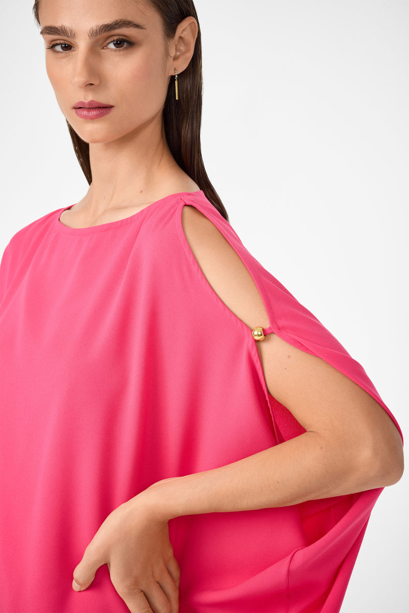 A woman models the Razu Short Split Sleeve Mini Dress, featuring bright pink fabric, open shoulder details, and gold button accents, as she poses confidently with her arm bent against a plain light background.