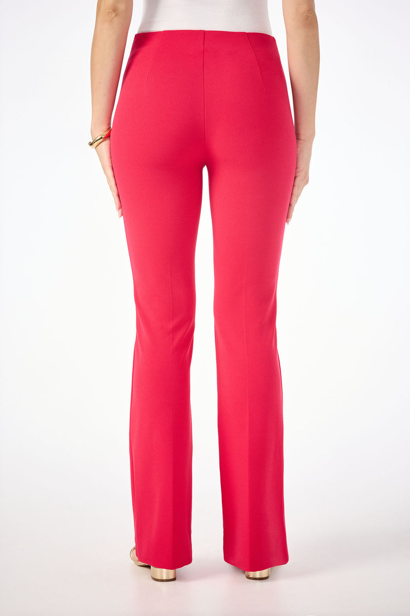 A woman faces away from the camera wearing Jacoba Slim-Fit Bootcut Pants in bright pink, paired with a white top and a gold bracelet. The background is plain white.