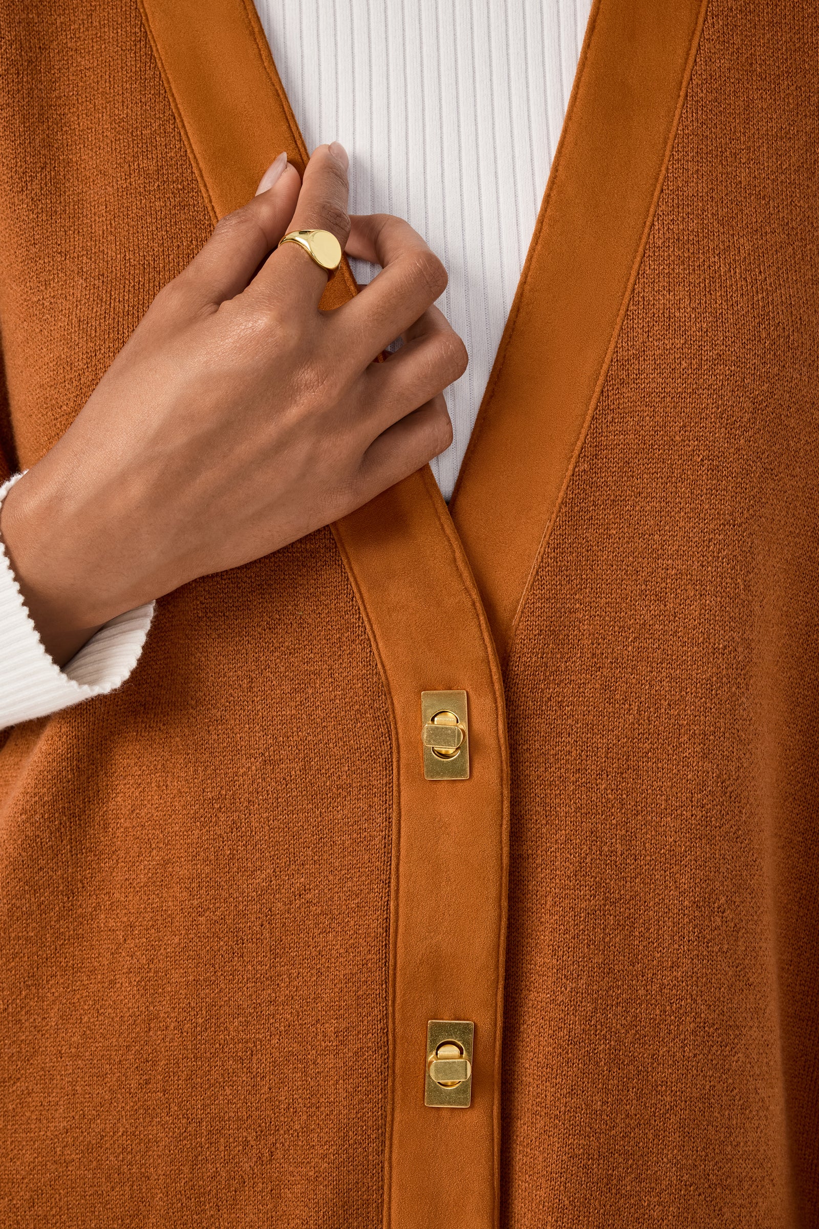 A person wearing the Sapphire Poncho over a white ribbed top, showing their hand with a gold ring resting on the poncho.