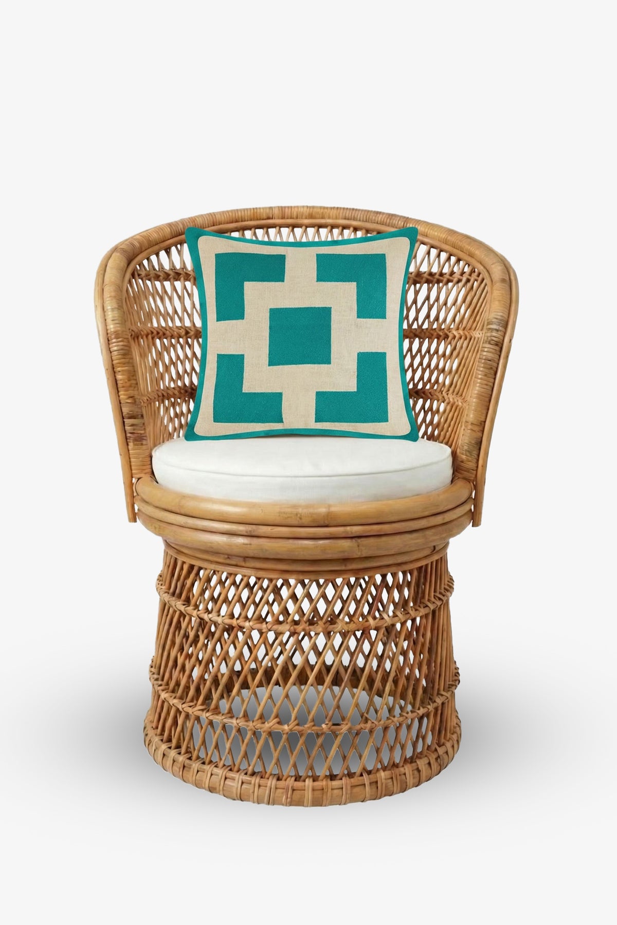 A wicker chair with a white cushion and a Palm Springs Block Embroidered Square Pillow in teal and white geometric patterns, filled with plush down feathers, set against a plain white background.