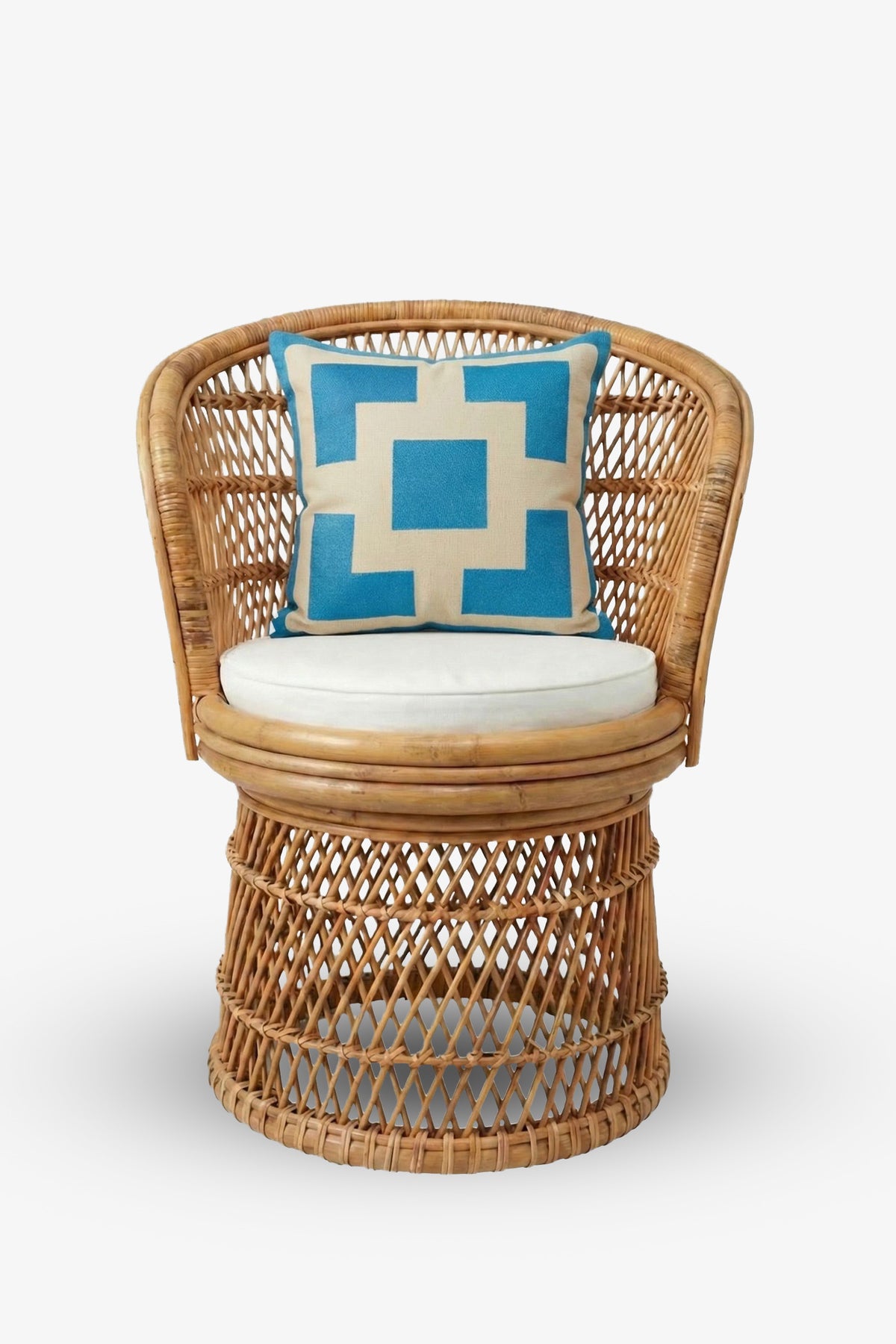 A round wicker chair with an open weave design and a beige seat cushion is accented by the Palm Springs Block Embroidered Square Pillow in blue and white geometric patterns, featuring a TRINA TURK HOME pillow cover with a plush down feather insert, placed on the backrest.