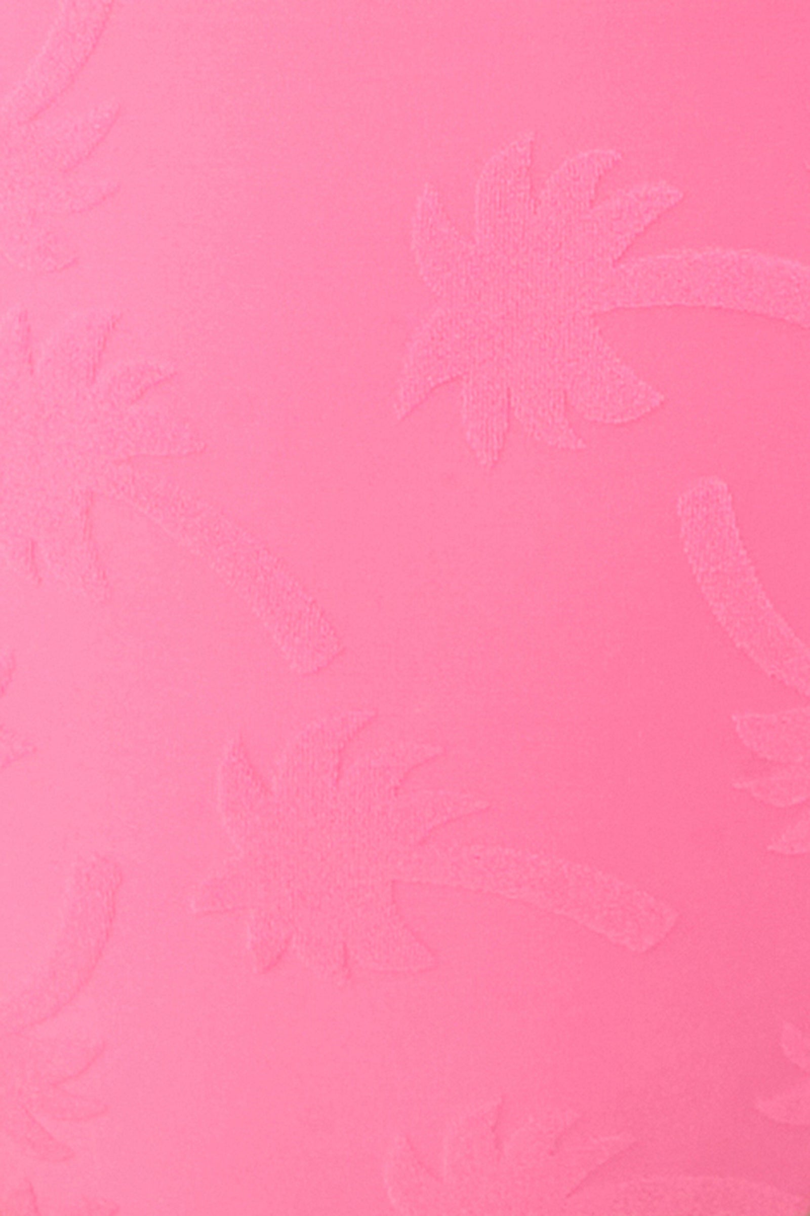 The Women’s Sway Ruffle Plunge One Piece Swimsuit features a pink textured surface with a subtle embossed palm tree pattern scattered across the background.