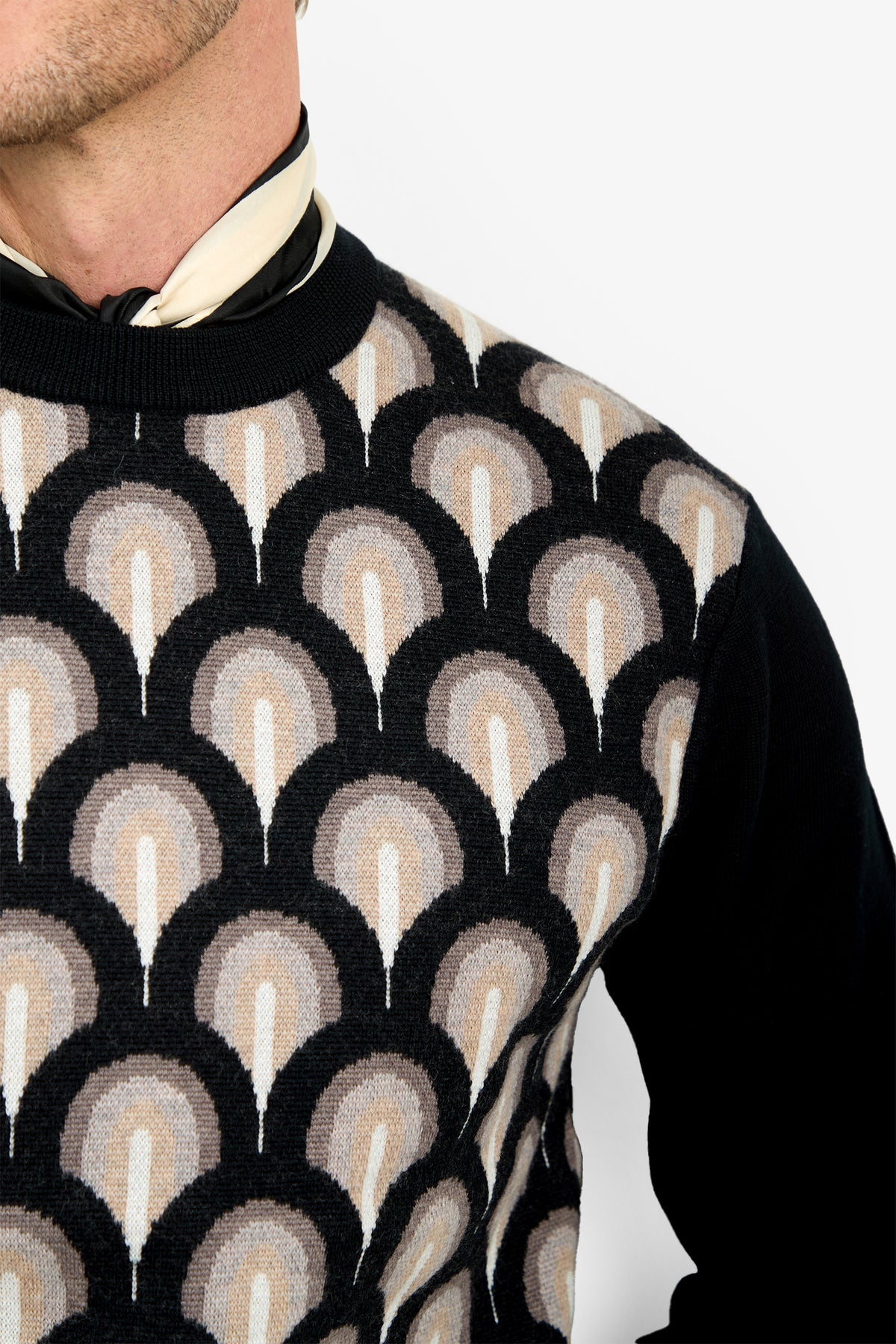 A person wears the Chrysler Sweater, featuring a geometric fan-shaped pattern in black, beige, and cream. The image focuses on the upper torso and neck against a white background.