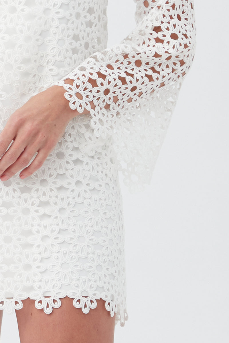 A woman models the Women's Chateau Lace Long Sleeve V-Neck Swim Cover-Up Dress with floral lace, bell sleeves, and scalloped edges—shown from torso to lower face against a plain background.