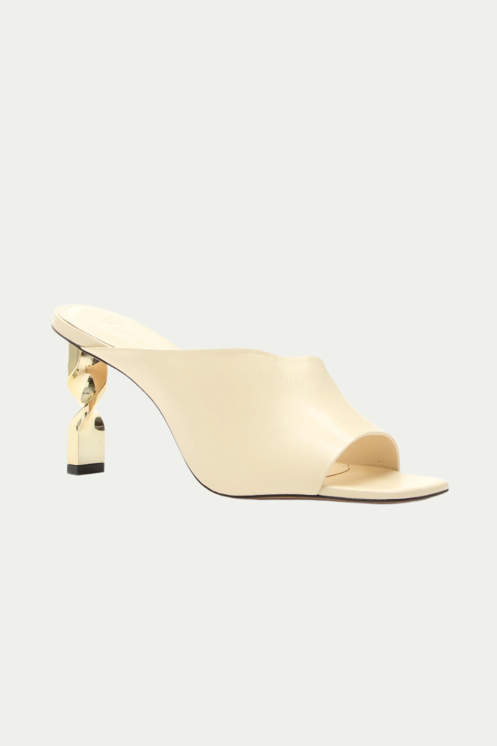 The Bariloche Leather Sculpted Heel Mule in white features an open toe and a sculptural gold metallic heel, shown against a plain light background.