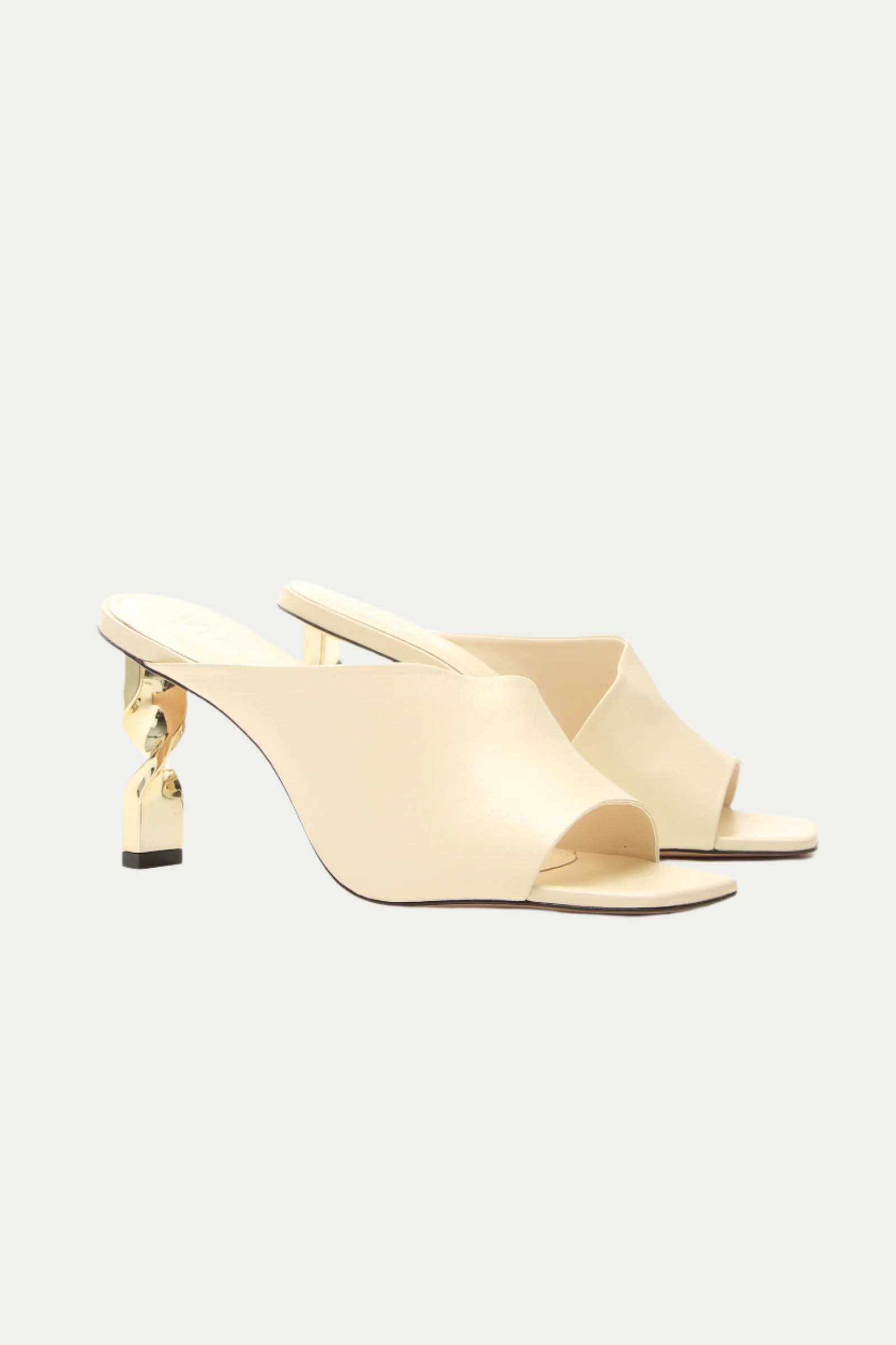 The Bariloche Leather Sculpted Heel Mule in white features a cream finish, open toe, and low gold sculpted heels, set against a clean light background.