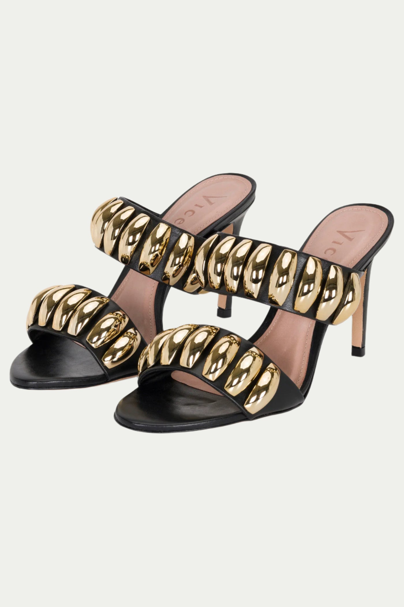 The GOLDEN VOLUME HEEL SANDAL is a black and gold pair of stilettos with two wide straps, each decorated with shiny gold oval embellishments.