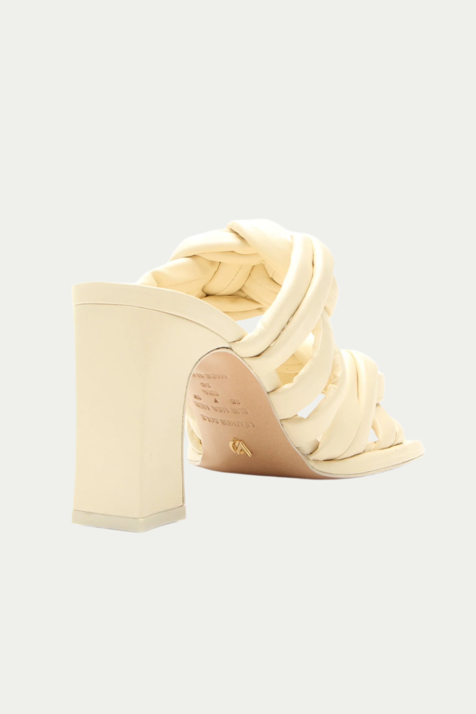 The Montpellier Leather Knot Heel Sandal in white features thick, braided straps and a cream-colored block heel, shown from the back right angle against a plain light background.