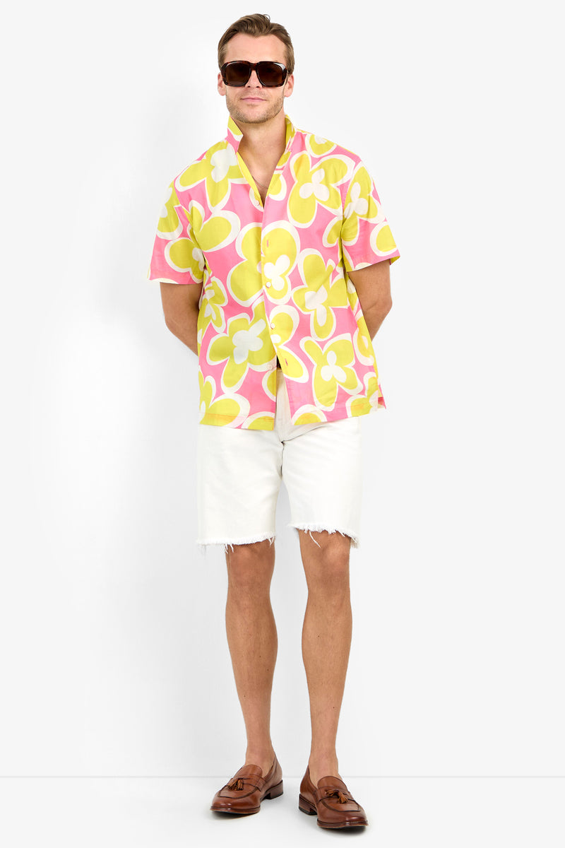 Man wearing the Felix Camp Shirt, white frayed shorts, brown loafers, and sunglasses stands against a plain white background with hands behind his back.