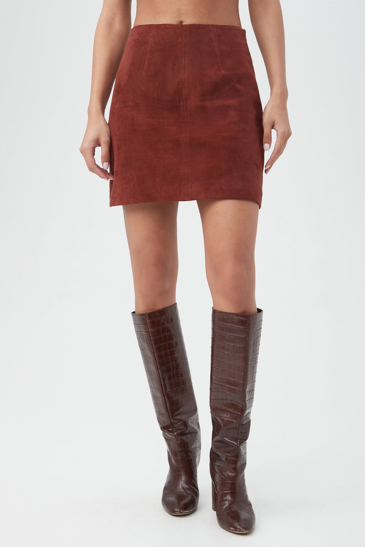 A person wearing the High Waisted Rico 2 Skirt in mahogany and knee-high, dark brown crocodile-textured boots stands against a plain white background.
