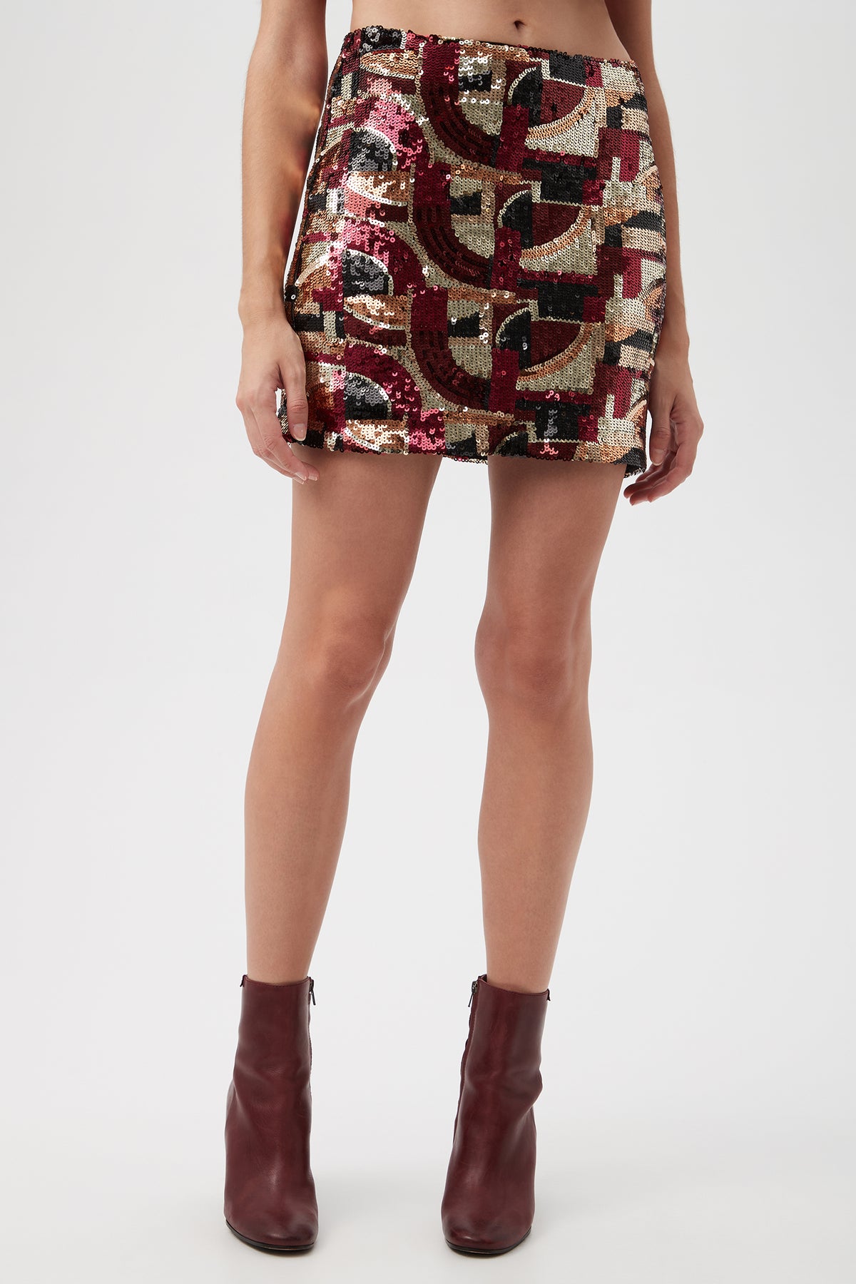 A person is wearing the Rico Galerie Arte Sequin Mini Skirt in multi, paired with burgundy ankle boots. The photo captures them from waist to feet.
