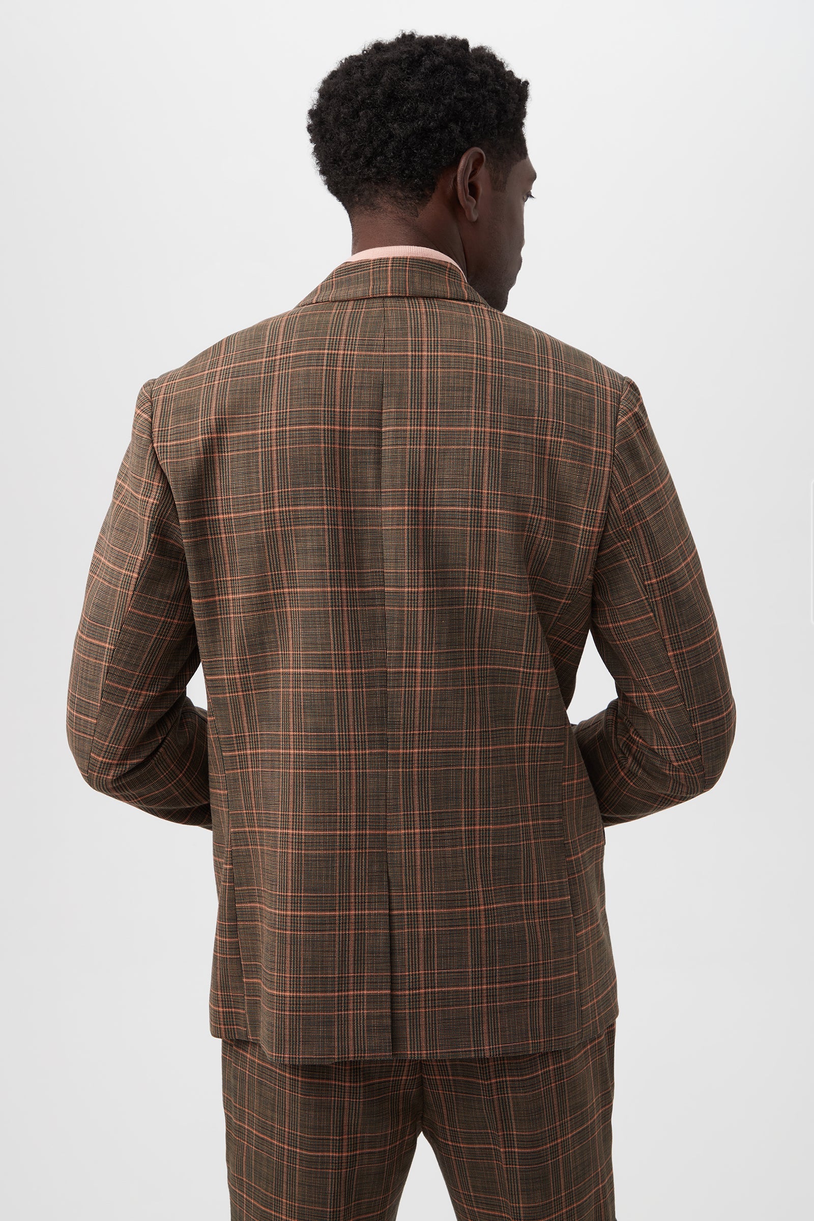 A man stands with his back to the camera in a Thurston 2 Blazer - Chaka Check Plaid, featuring brown plaid with red and beige lines, against a plain white background.
