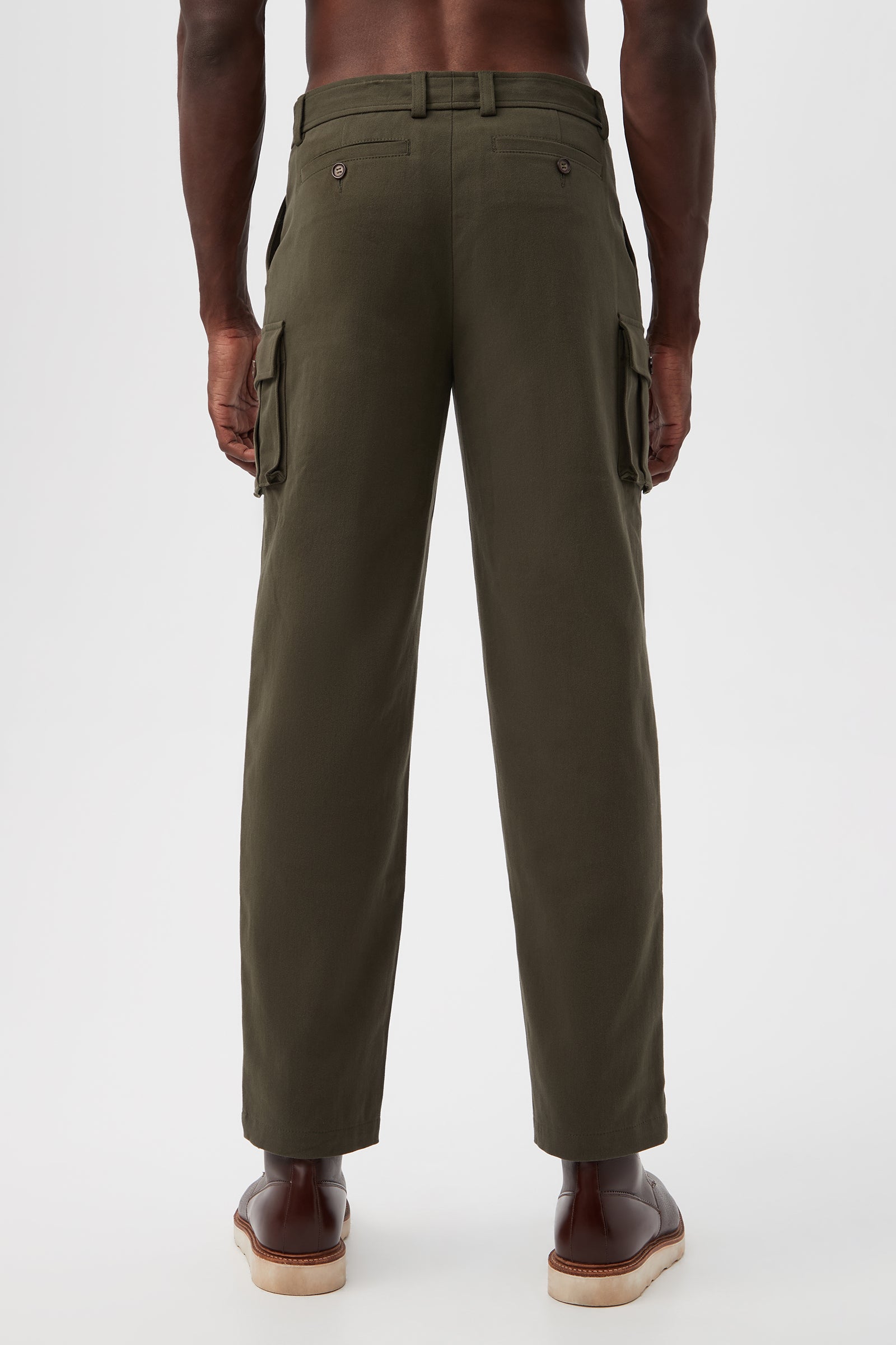 A man stands facing away in Lincoln Heights Cargo Trouser - Brushed Twill in olive green with side pockets and brown dress shoes, set against a plain white background.