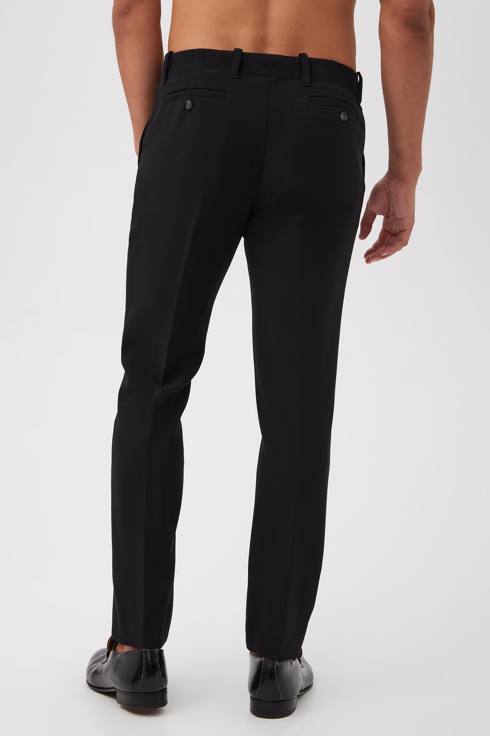 A person is shown from the back wearing the Alex Slim Trouser - Luxe Drape in black with black shoes, standing shirtless against a plain white background.
