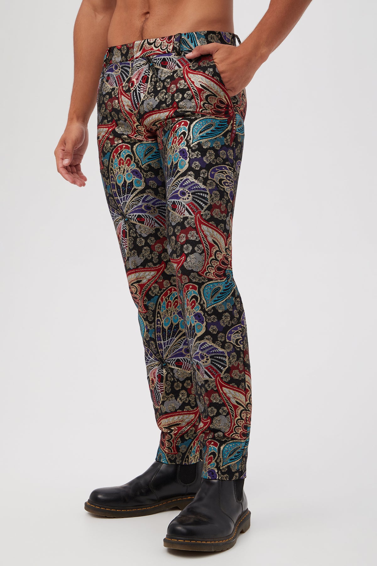 A person wears the Clyde Slim Trouser in Monarch Jacquard with black boots, standing against a white background with one hand in their pocket and upper body mostly out of frame.