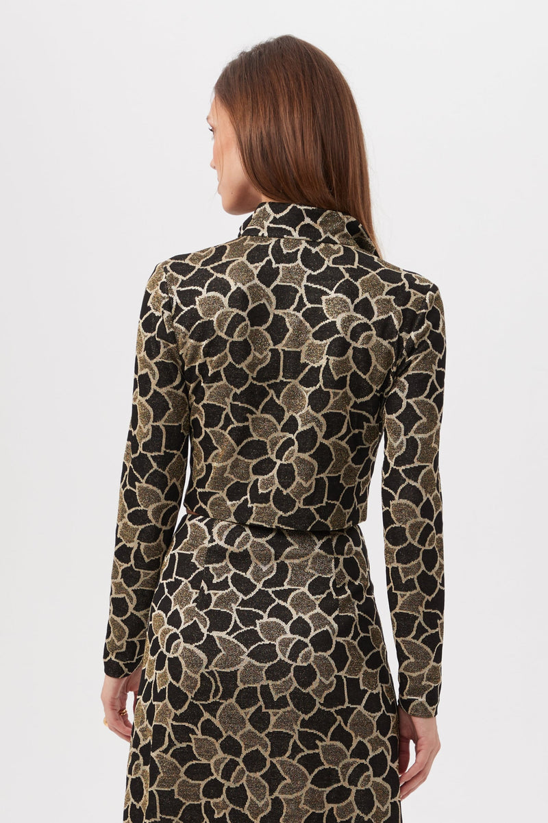 A woman with long brown hair, seen from the back, wears the Frosty Meadows Cropped Knit Jacquard Zip-Front Top against a plain white background.