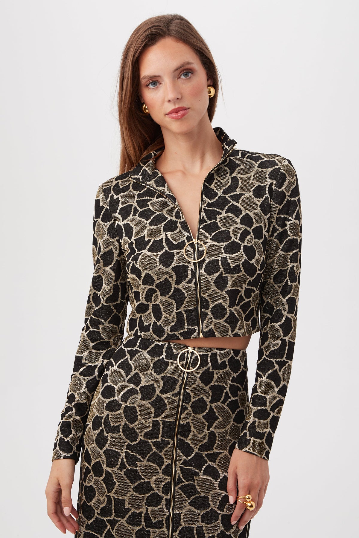 A woman wears the Frosty Meadows Cropped Knit Jacquard Zip-Front Top in Multi, paired with a matching skirt, standing against a plain white background.