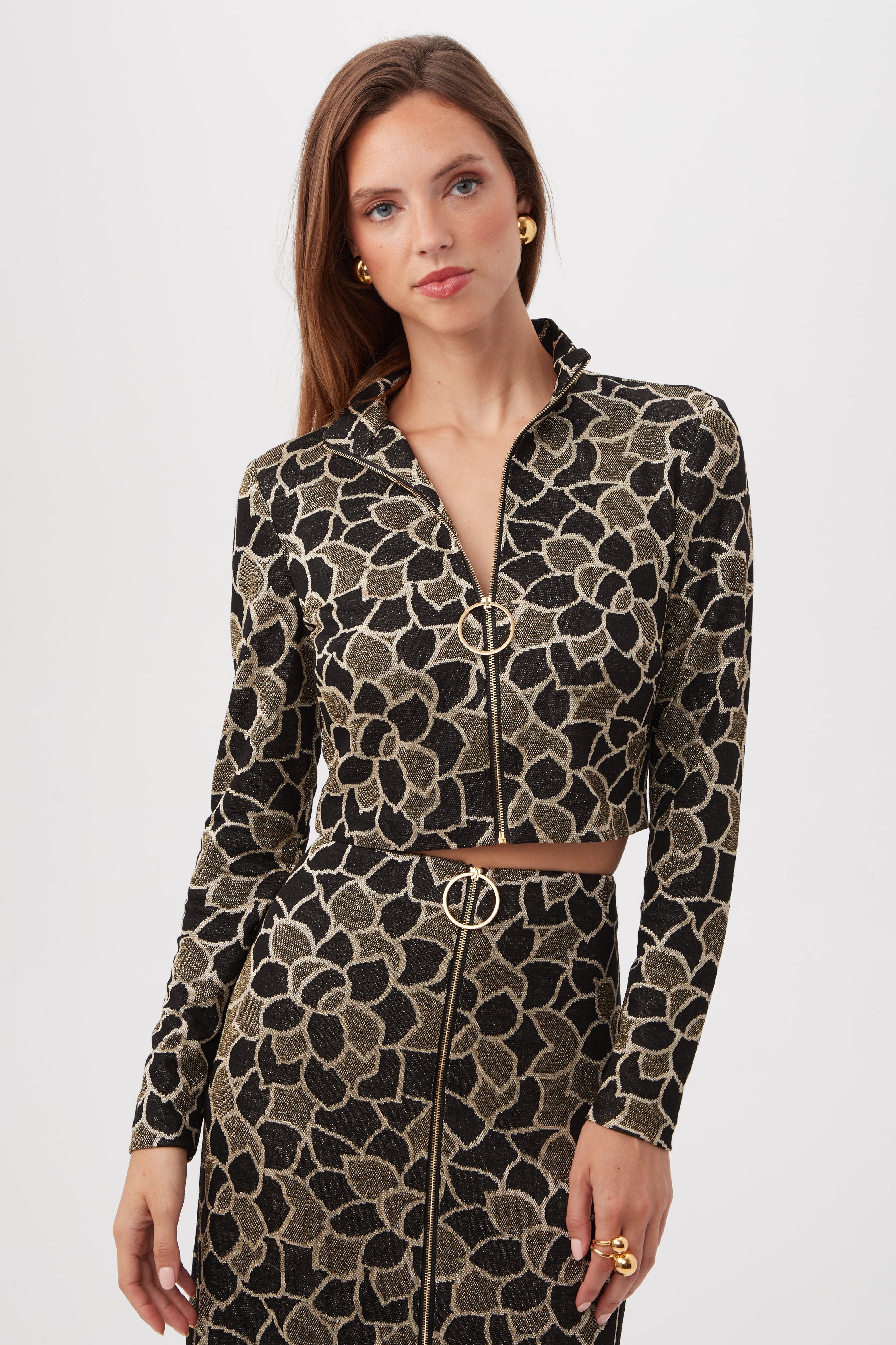 A woman wears the Frosty Meadows Cropped Knit Jacquard Zip-Front Top in Multi, paired with a matching skirt, standing against a plain white background.