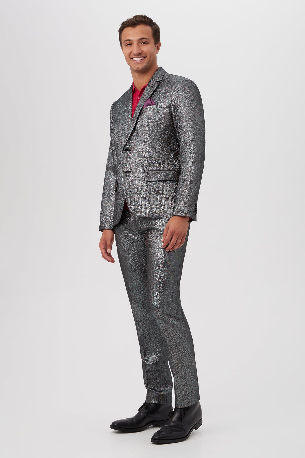 A man smiles while standing against a plain white background, wearing the Thurston Blazer - Mini Stained Glass Jacquard with a red shirt and black dress shoes.