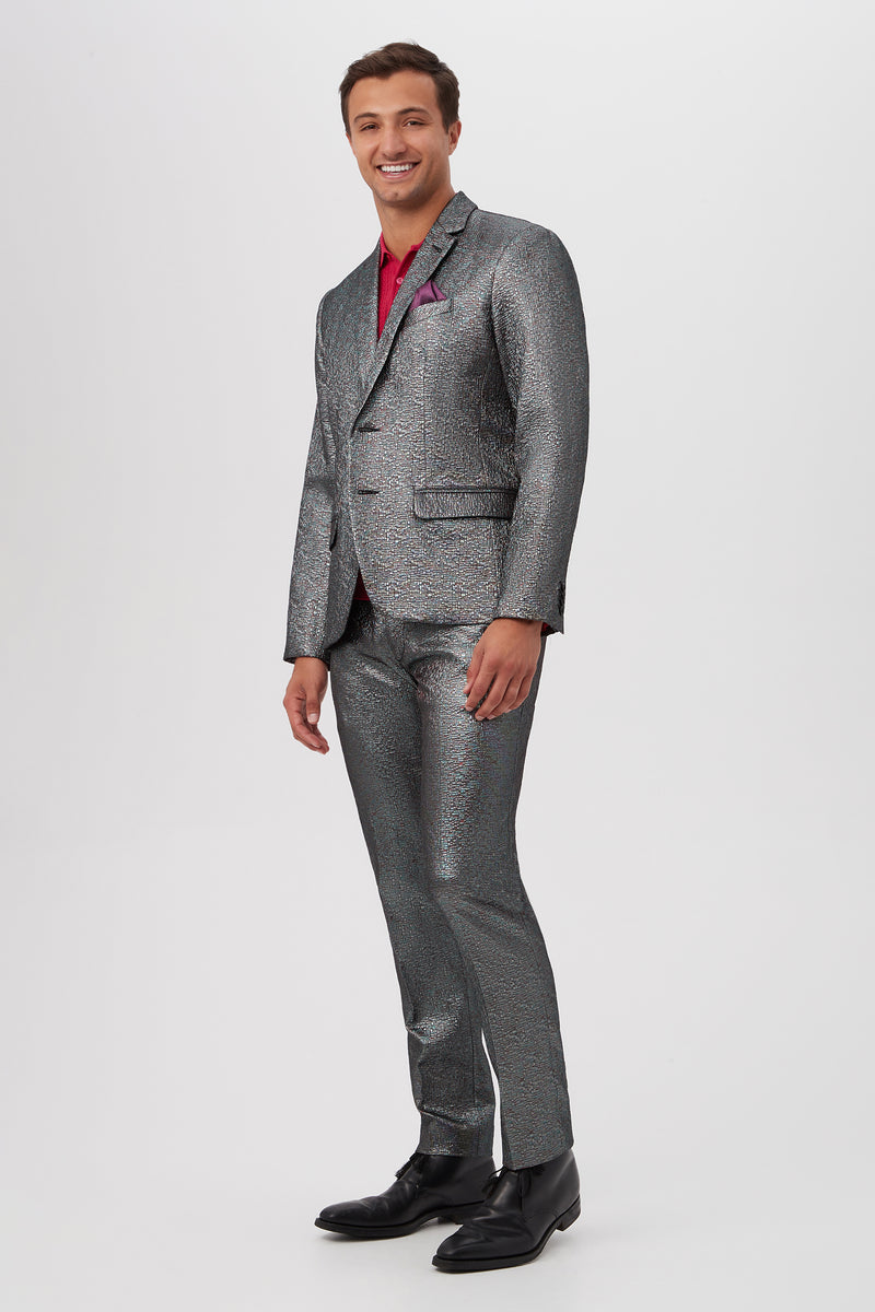 A man smiles while standing against a plain white background, wearing the Thurston Blazer - Mini Stained Glass Jacquard with a red shirt and black dress shoes.