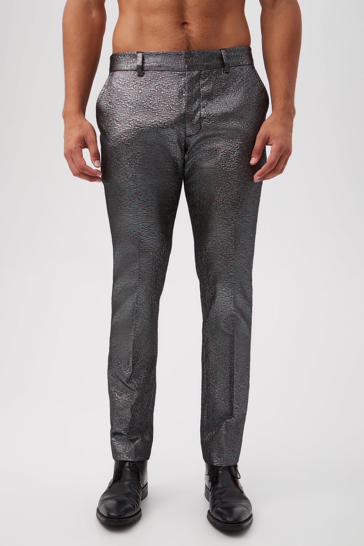 A man wearing the Clyde Slim Trouser in Stained Glass Jacquard (Multi) with a black belt and black dress shoes stands against a white background. The image is cropped at the chest, showing only his lower torso and legs.