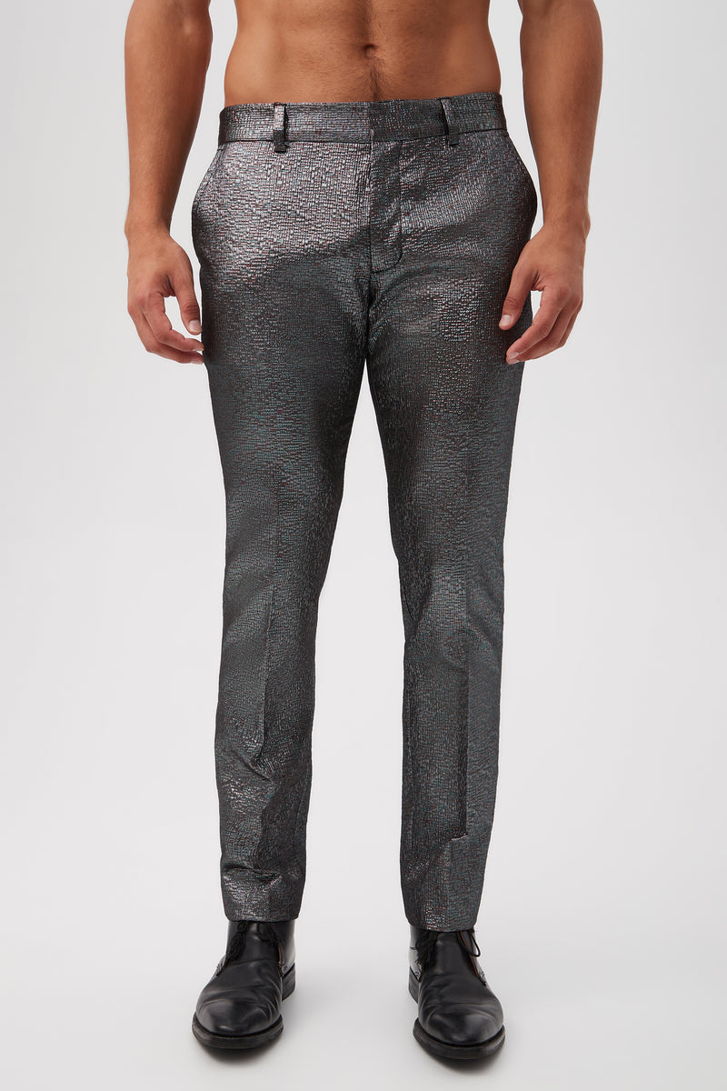 A man wearing the Clyde Slim Trouser in Stained Glass Jacquard (Multi) with a black belt and black dress shoes stands against a white background. The image is cropped at the chest, showing only his lower torso and legs.