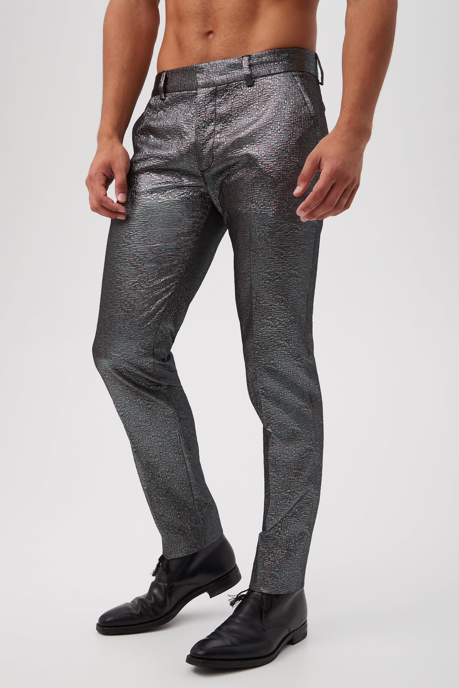 A man stands against a plain background wearing the Clyde Slim Trouser - Stained Glass Jacquard and black dress shoes, with his upper body bare to reveal his torso and arms.