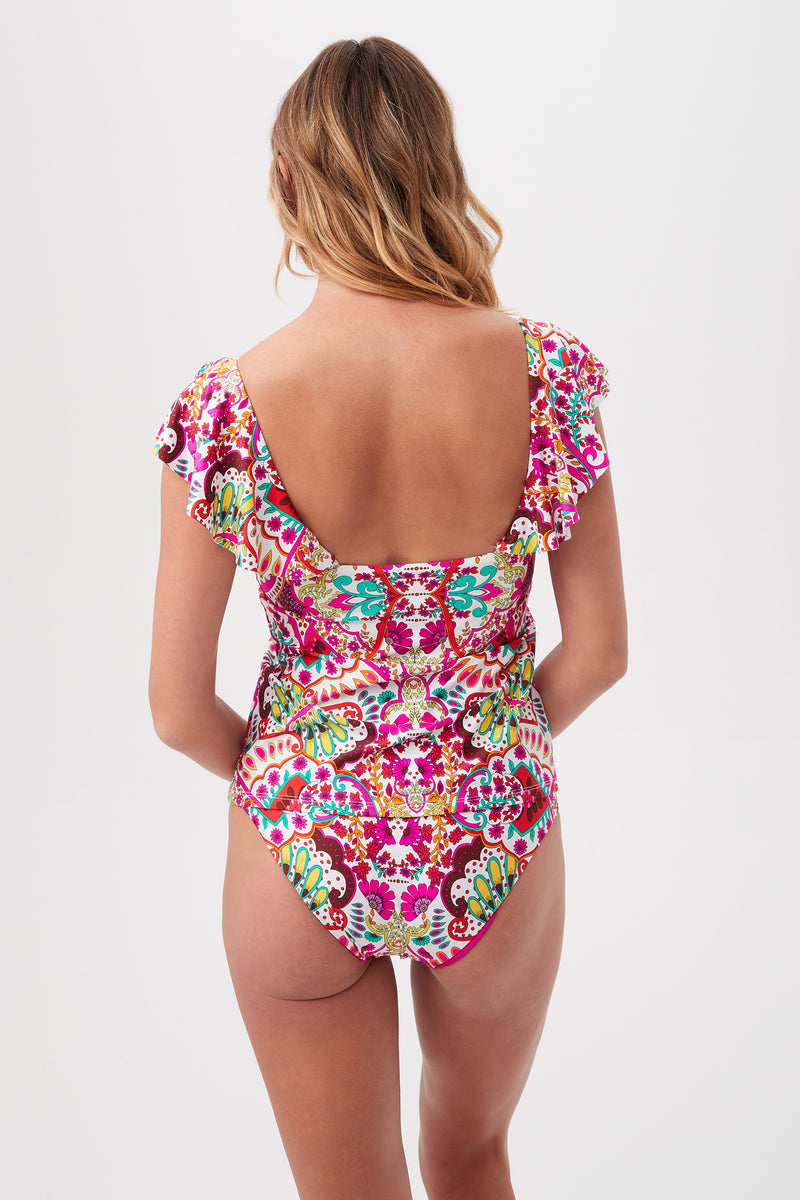A woman with wavy hair is shown from the back wearing the Hawaiian Garden Ruffle V-Neck Tankini Swim Top, featuring colorful patterned fabric and ruffled sleeves, against a plain white background.