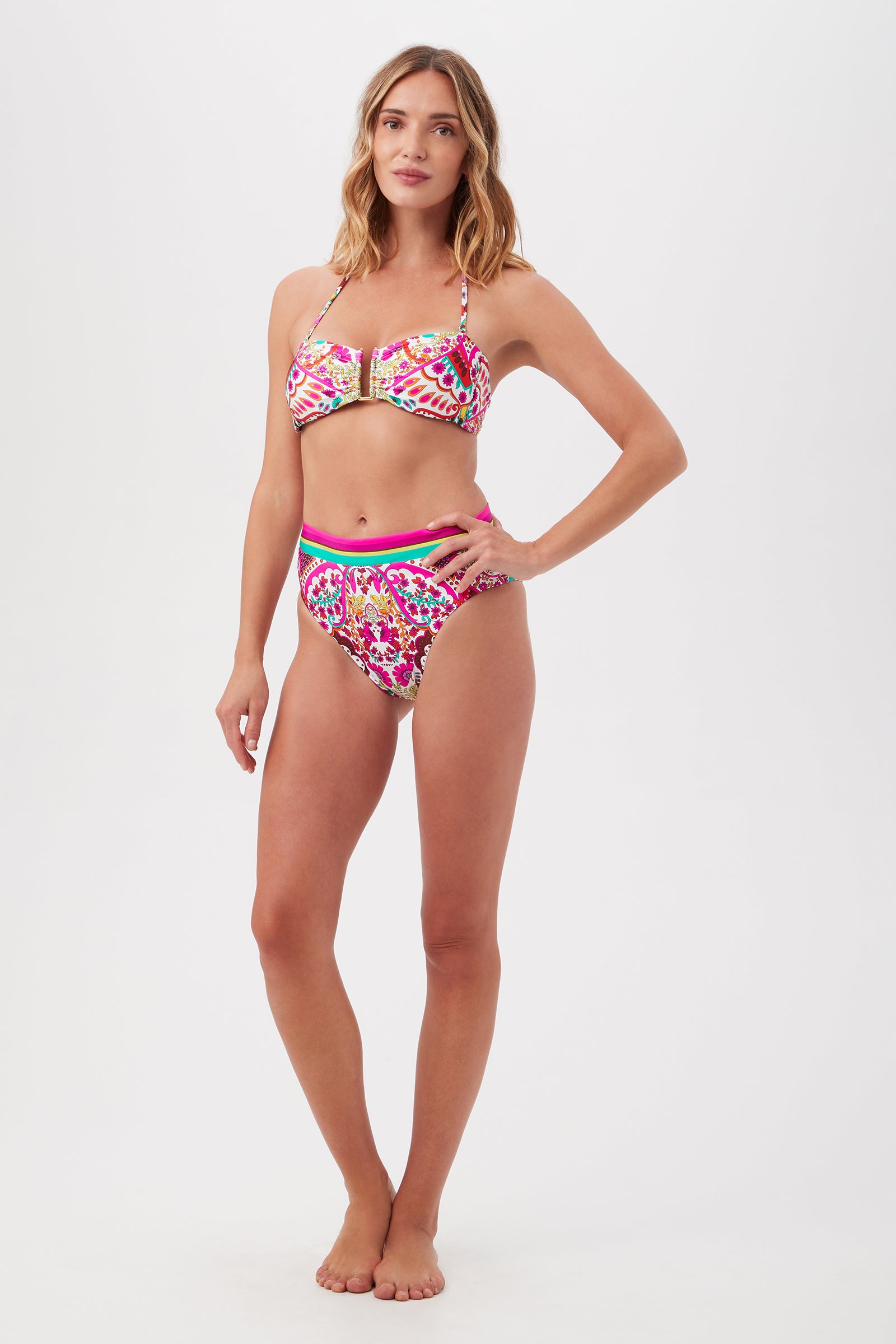 A woman poses against a white background wearing the Hawaiian Garden U-Wire Strapless Bandeau Swim Top and high-waisted bottoms, featuring vibrant pink, gold, and green patterns.