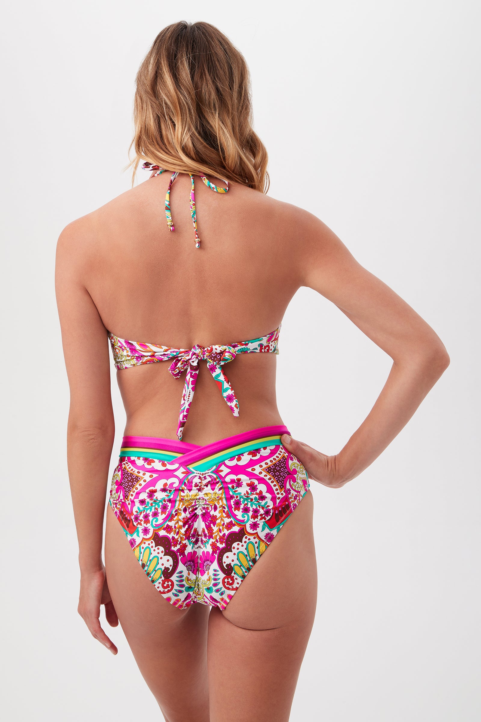 A woman with wavy, shoulder-length hair wears the Hawaiian Garden U-Wire Strapless Bandeau Swim Top and high-waisted bottoms, both in colorful pink, green, and yellow patterns for a lively look. Shown from the back.
