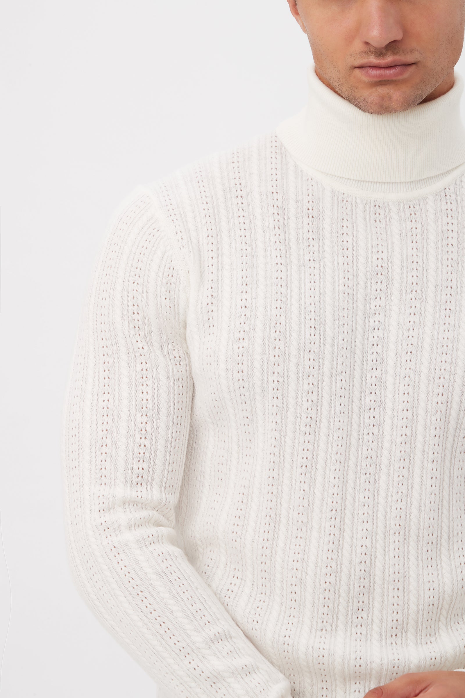 A man wears the Oberon Turtleneck Sweater - Merino Wool in white, featuring a ribbed texture. Shown from shoulders to mid-torso against a plain white background, his face is partially out of the frame.